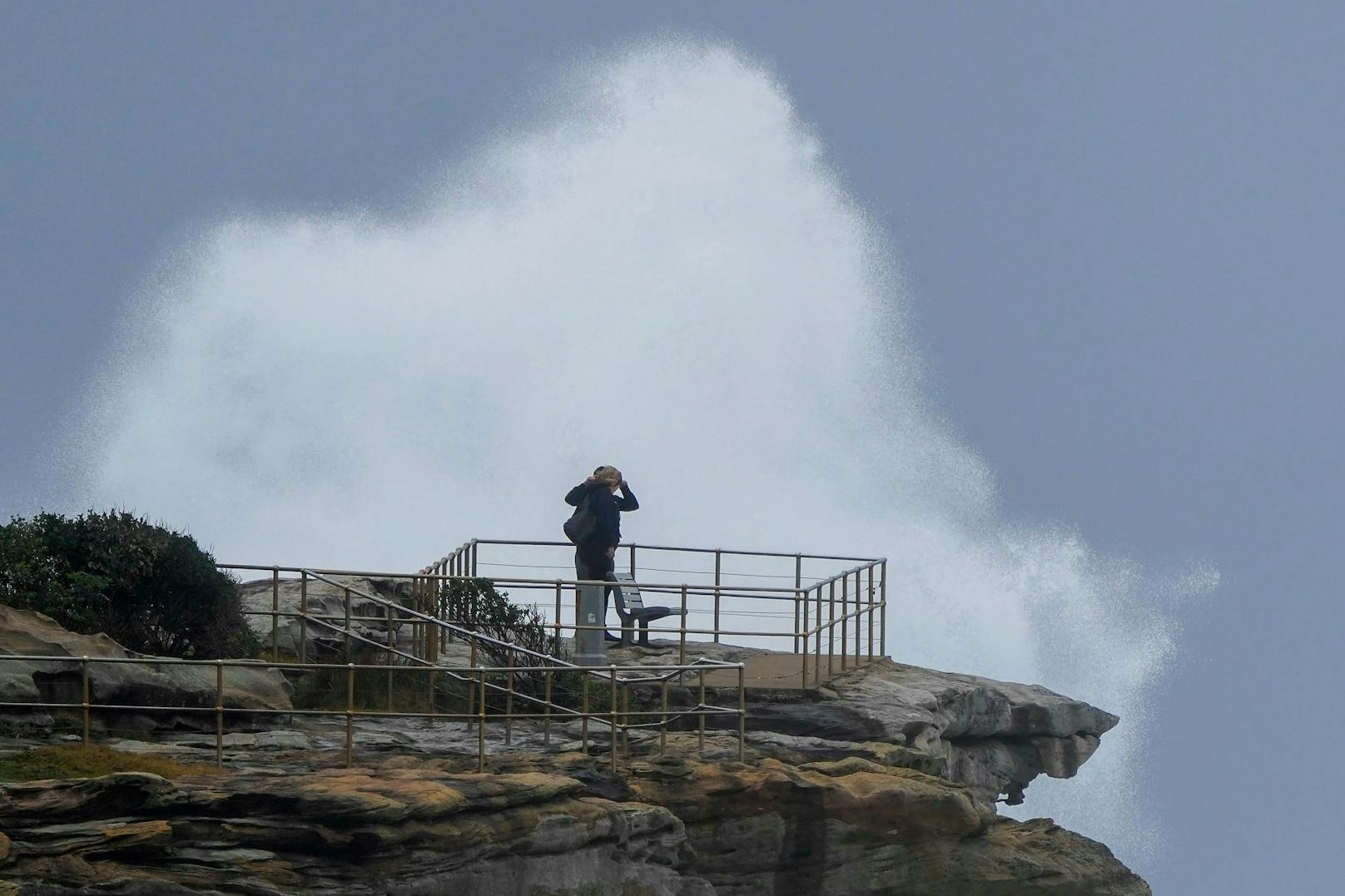 Menschen stehen auf einem Felsvorsprung, als riesige Wellen auf die Landzunge am Bondi Beach in Sydney, Australien, treffen, Sonntag, 3. Juli 2022.&nbsp;