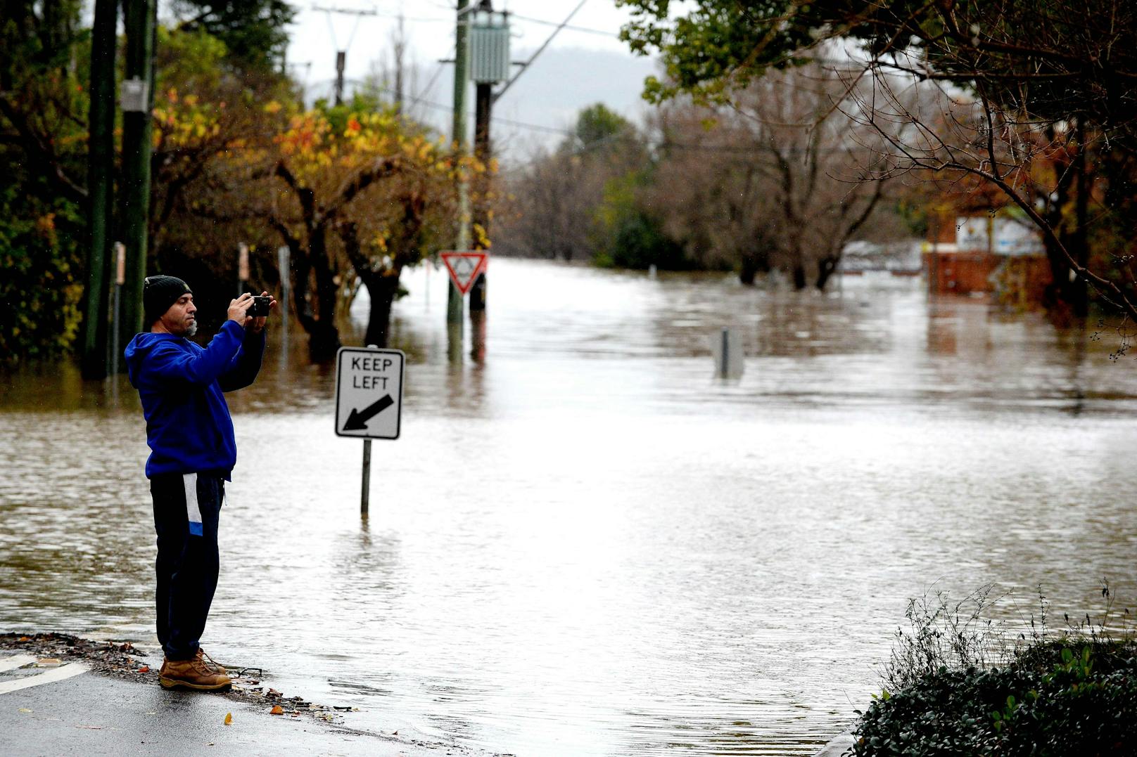 Ein Mann fotografiert die überschwemmten Straßen im Vorort Camden in Sydney am 3. Juli 2022.