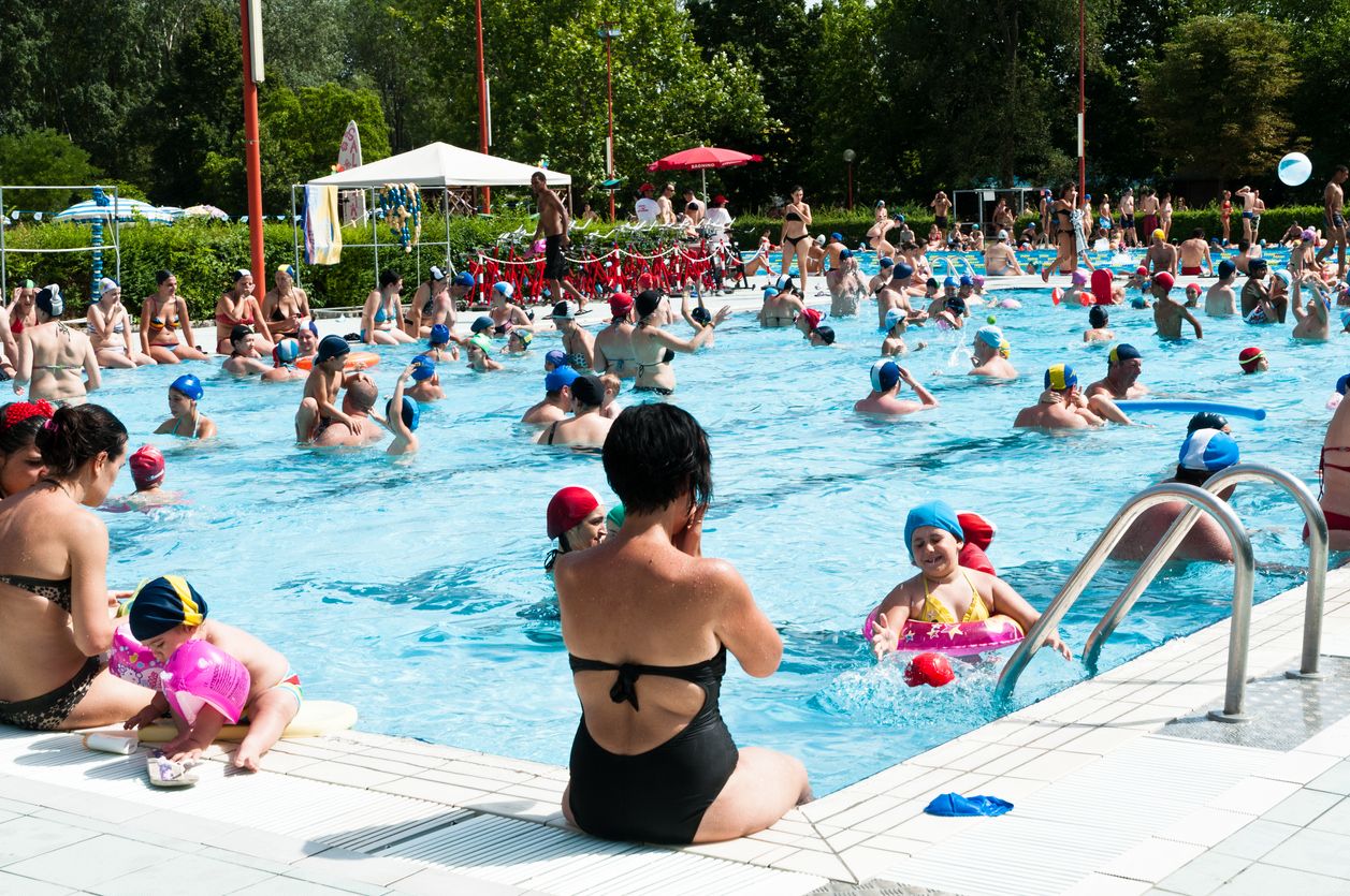 "Bologna, Italy - July 1, 2012: Adulta and families with children refreshing themself and having fun in a crowded swimming pool near Bologna (Italy). It's a sunny day, during a very hot summer."