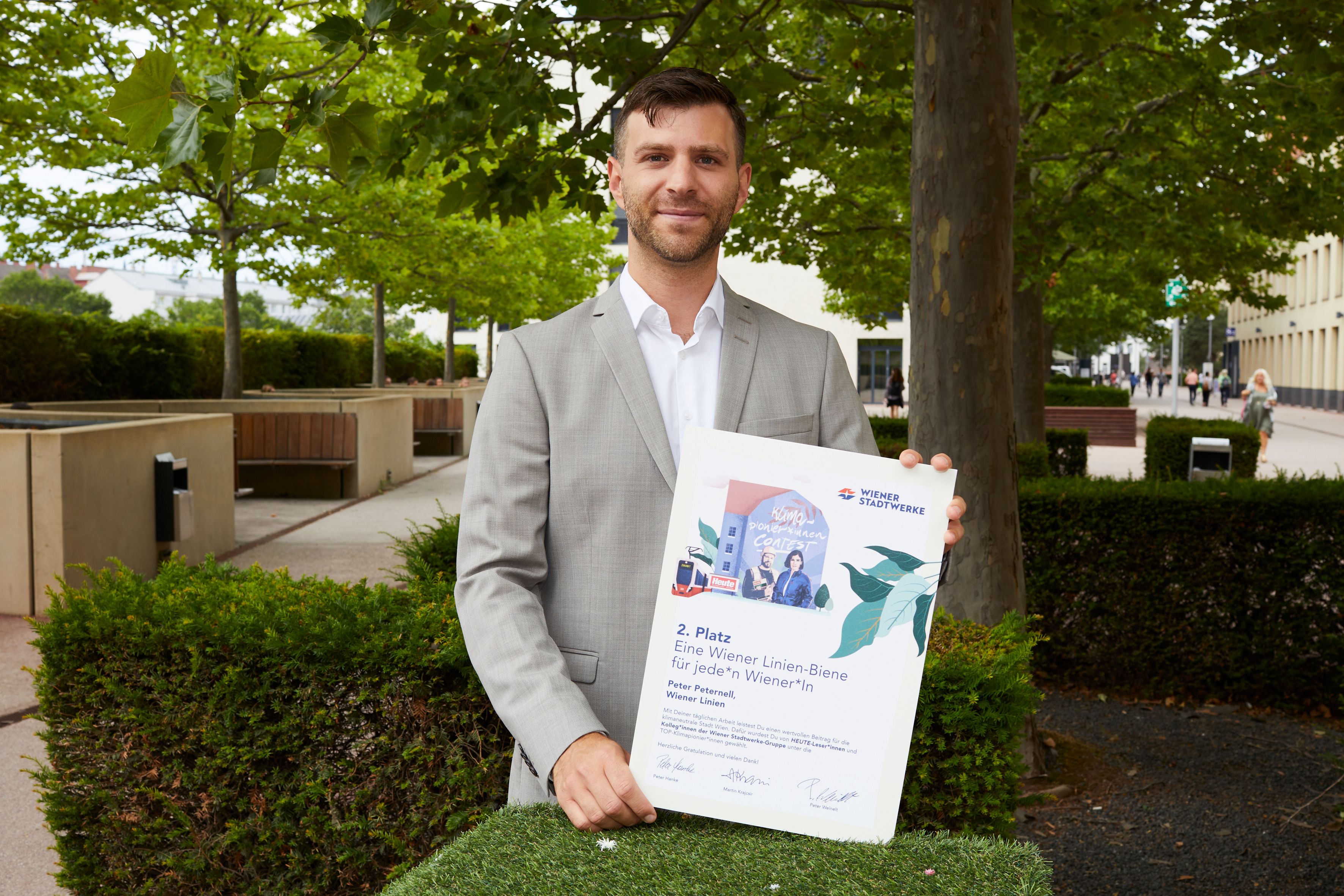 Peter Peternell präsentiert die Auszeichnung für den zweiten Platz für sein Projekt "Eine Wiener Linien-Biene für jede*n Wiener*in".