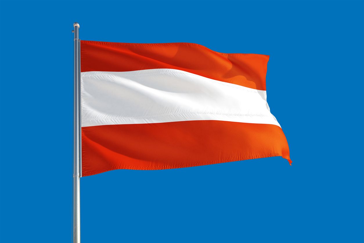 Austria national flag waving in the wind on a deep blue sky. High quality fabric. International relations concept.