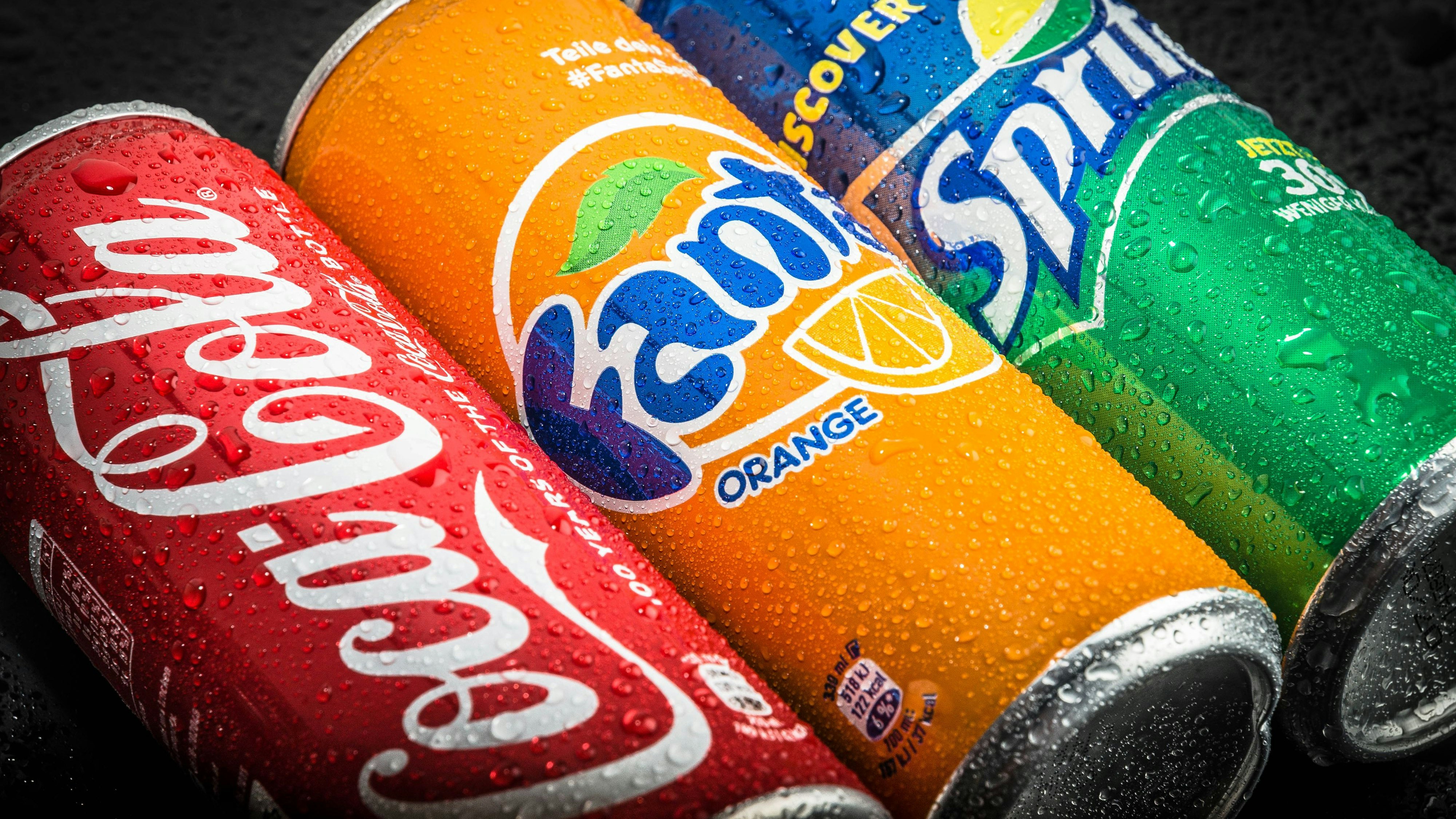 Leonding, Austria - June 16, 2015: A can of Coca Cola, Sprite and Fanta on black background covered with waterdrops. It is produced by The Coca-Cola Company of Atlanta, Georgia.