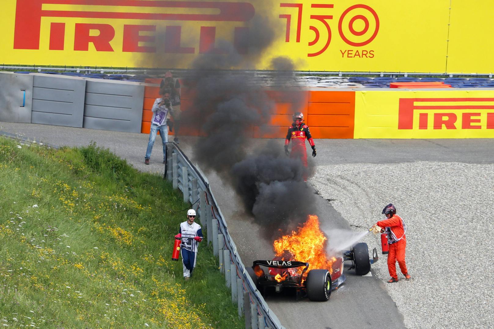 Die Streckenposten löschen den Brand am Ferrari von Carlos Sainz. 