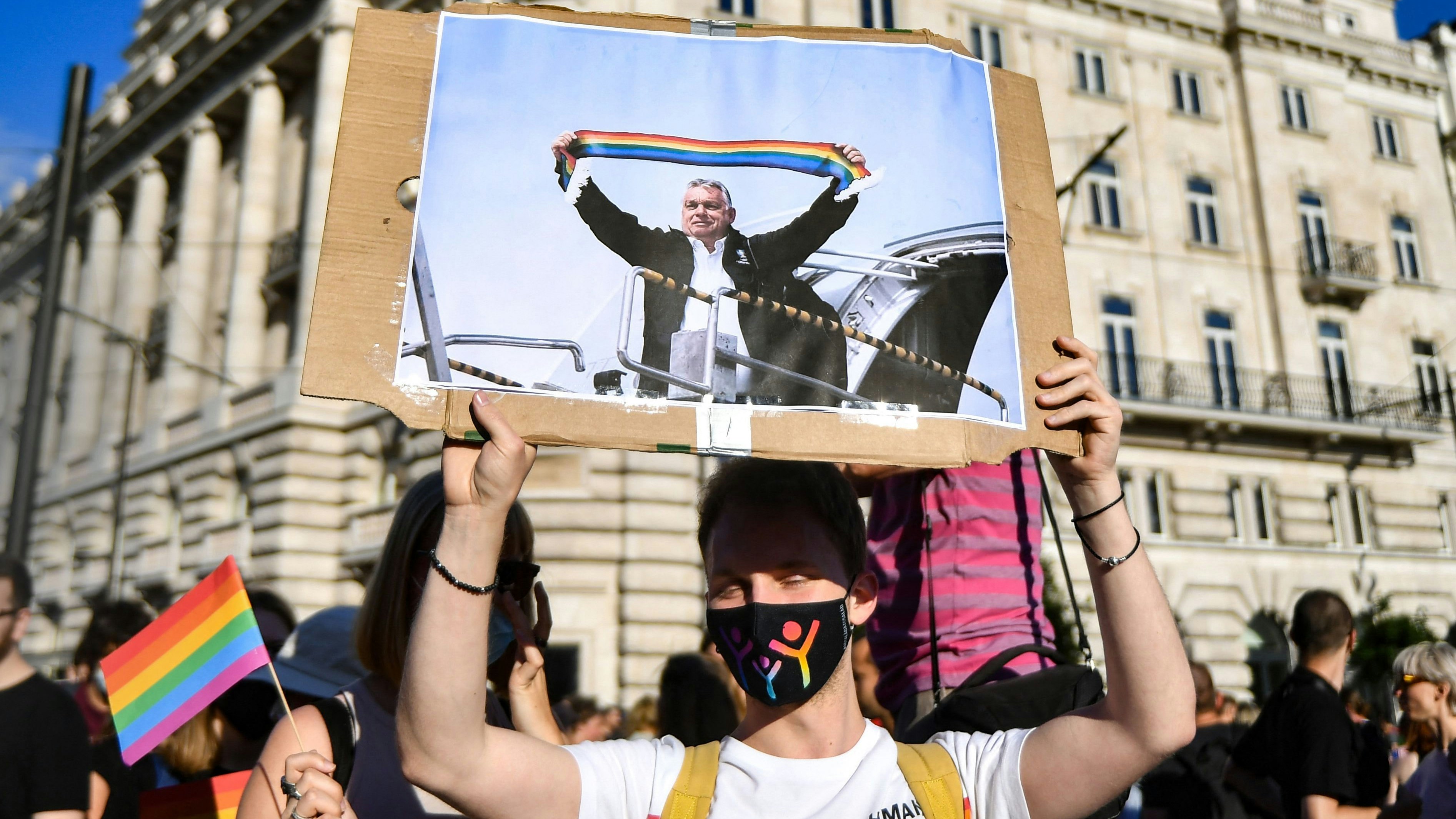 Download von www.picturedesk.com am 16.07.2022 (08:56).  (FILES) In this file photo taken on June 14, 2021 a participant holds a placard showing Hungarian Prime Minister Viktor Orban holding a scarf in rainbow colours, in front of the parliament building in Budapest, during a demonstration against the Hungarian government's draft bill seeking to ban the "promotion" of homosexuality and sex changes. - Hungary's Prime Minister Viktor Orban said on July 21, 2021 that a referendum would be held to gauge domestic support for a controversial LGBTQ law, after the European Commission launched legal action against Budapest over the measure. (Photo by GERGELY BESENYEI / AFP) - 20210614_PD15670 - Rechteinfo: Rights Managed (RM) Nur für redaktionelle Nutzung! Werbliche Nutzung erfordert Freigabe: bitte schicken Sie uns eine Anfrage.
