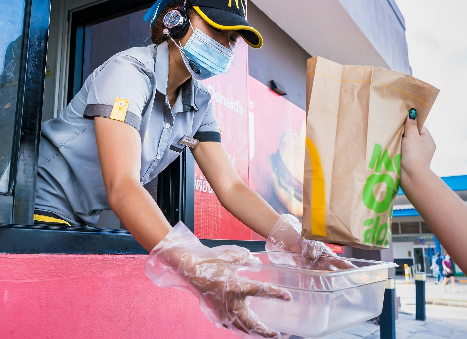 Eine Angestellte reicht eine Bestellung durch das Fenster des Drive-In-Schalters. Symbolbild