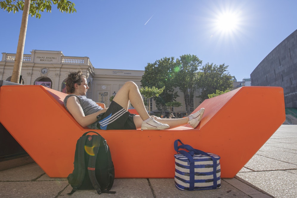 Ein Mann genießt die Sonne auf einer Liegeinsel im Museumsquartier in Wien.