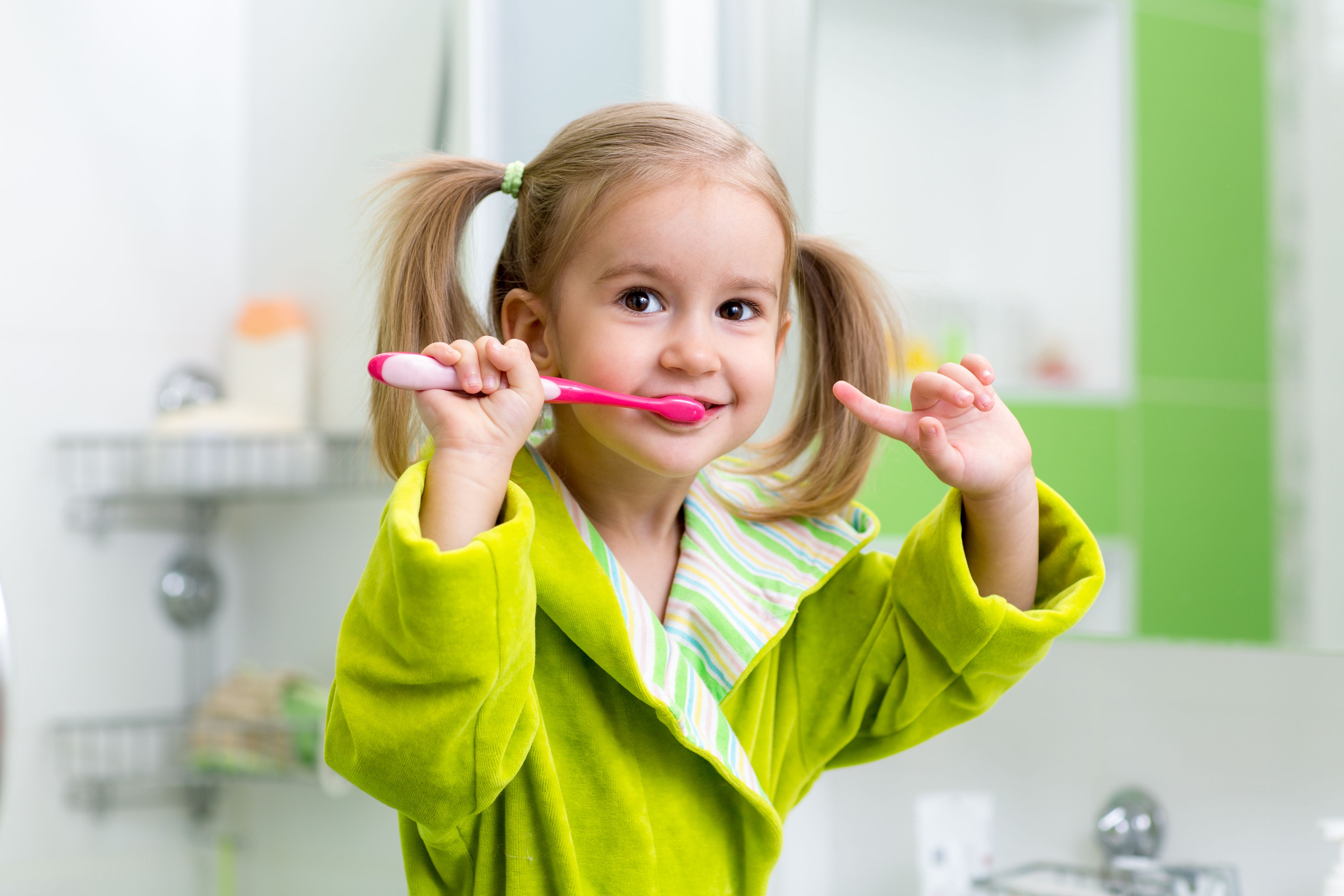 Smiling kid child girl brushing teeth in bathroom