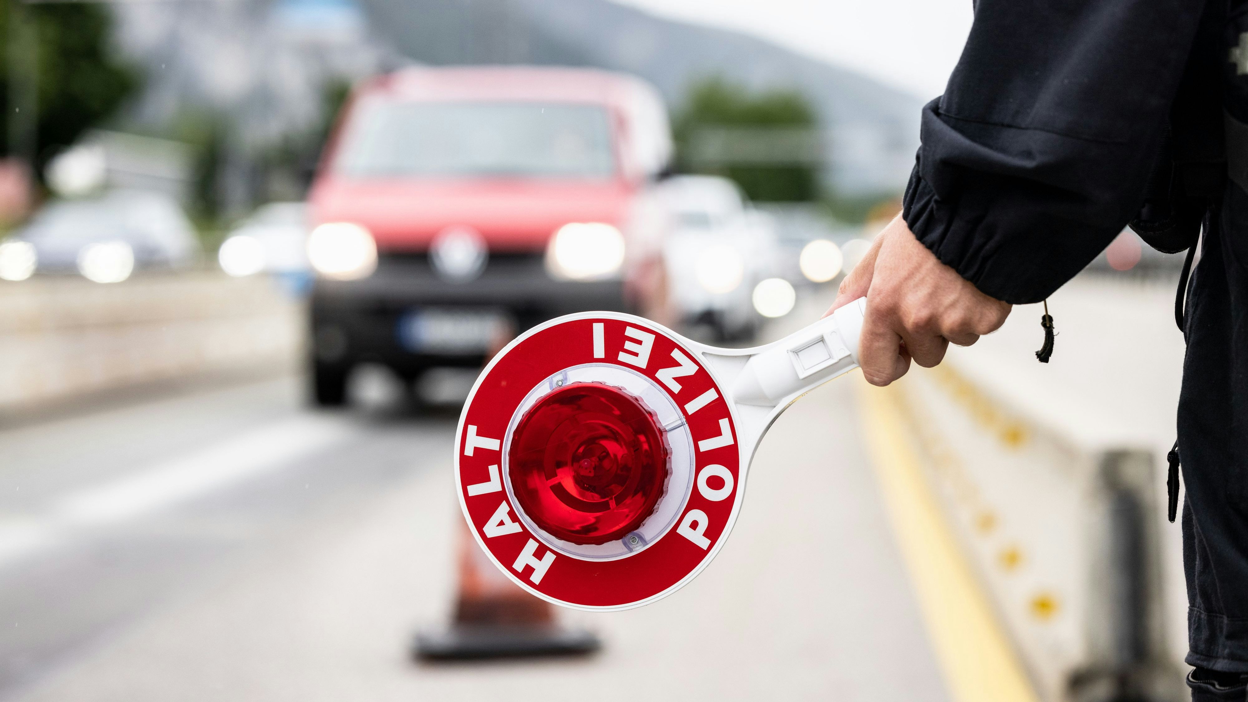 Download von www.picturedesk.com am 26.07.2022 (12:13).  FILED - 01 August 2021, Bavaria, Kiefersfelden: A German federal police officer holds a ladle with the inscription "Halt Polizei" at a checkpoint on the border with Austria on Autobahn 93 near Kiefersfelden. Photo: Matthias Balk/dpa - 20210801_PD32268 - Rechteinfo: Rights Managed (RM)
