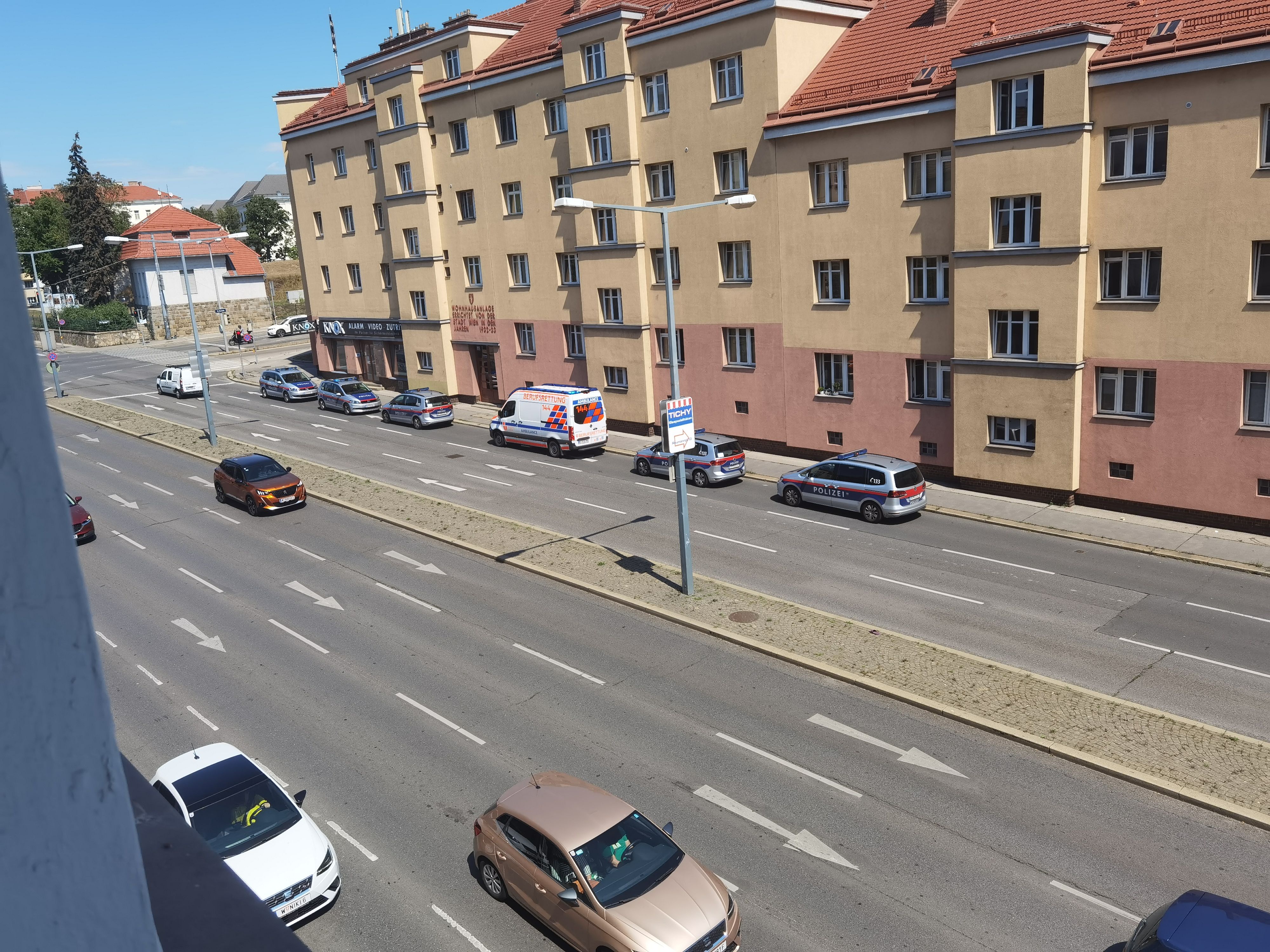 Mehrere Einsatzkräfte der Wiener Polizei und der Berufsrettung vor dem Gemeindebau.
