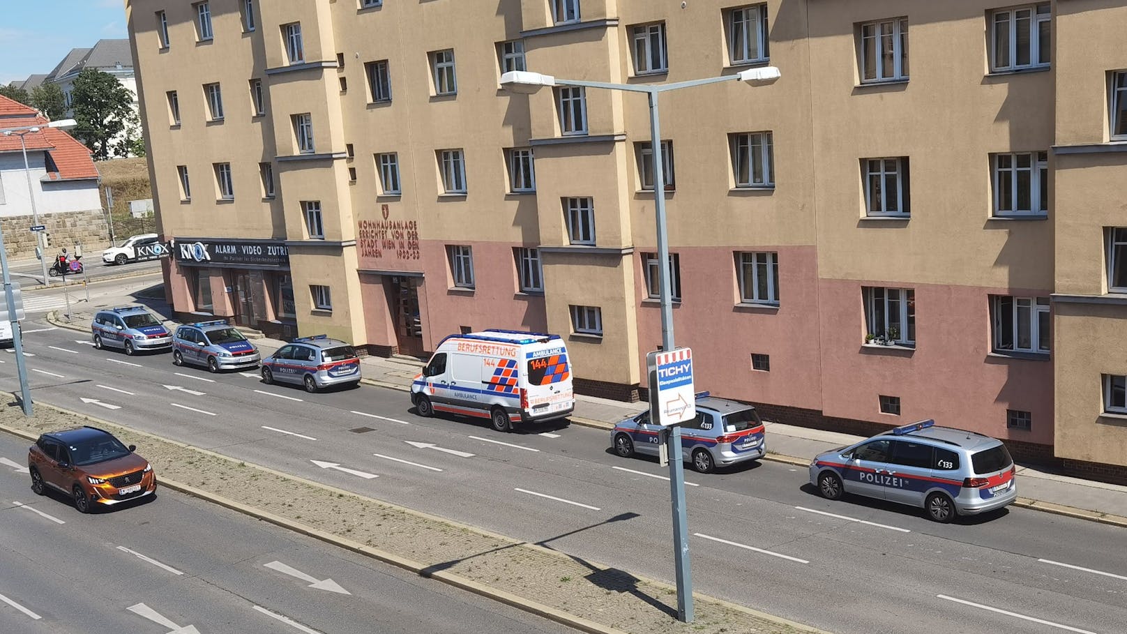Mehrere Einsatzkräfte der Wiener Polizei und der Berufsrettung vor dem Gemeindebau.