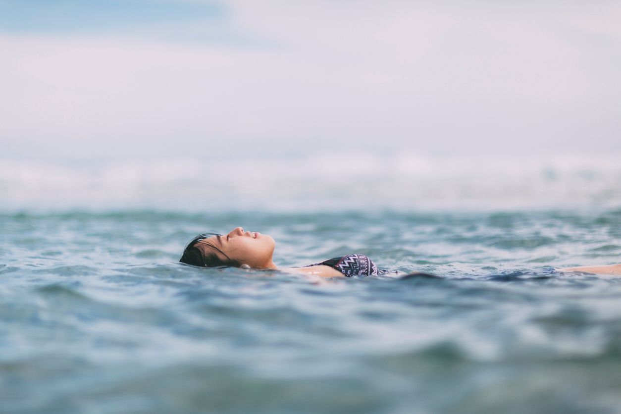 A young Japanese woman is floating in the sea.