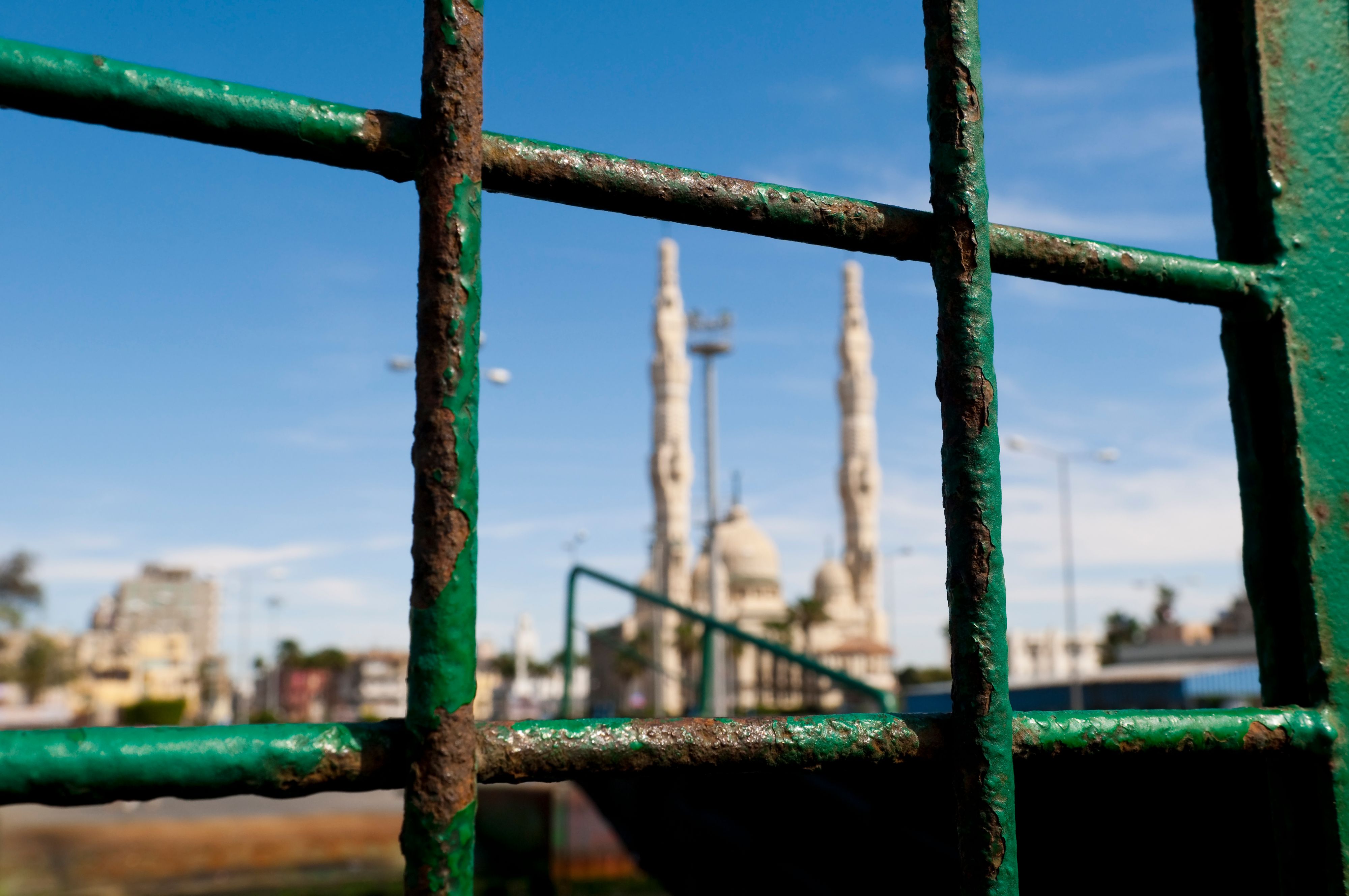 The view of a mosque through a rusting iron cage. Location: Port Said, Egypt