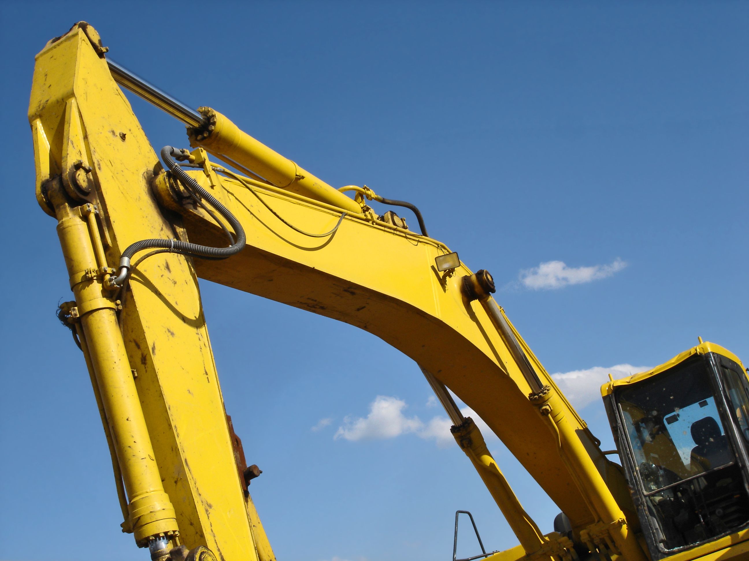 An angled view of an earth mover at a construction site, set against a blue sky.