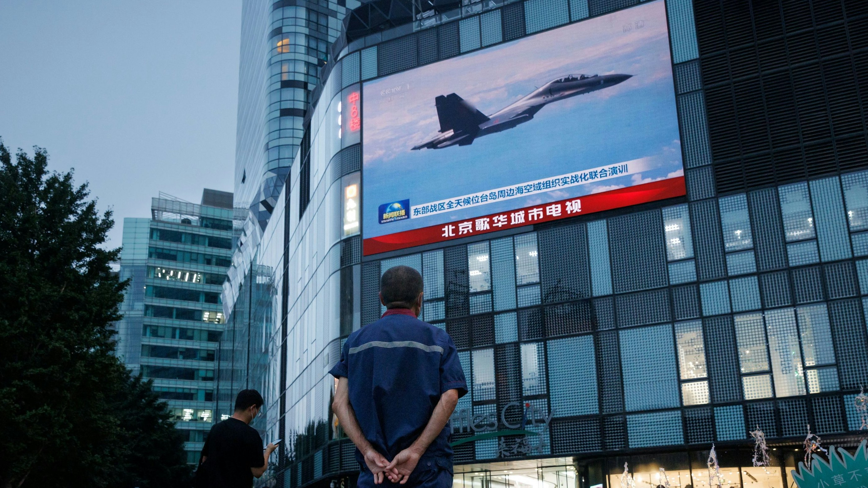 A man watches a CCTV news broadcast, showing a fighter jet during joint military operations near Taiwan by the Chinese People's Liberation Army's (PLA) Eastern Theatre Command, at a shopping center in Beijing, China, August 3, 2022. REUTERS/Thomas Peter
