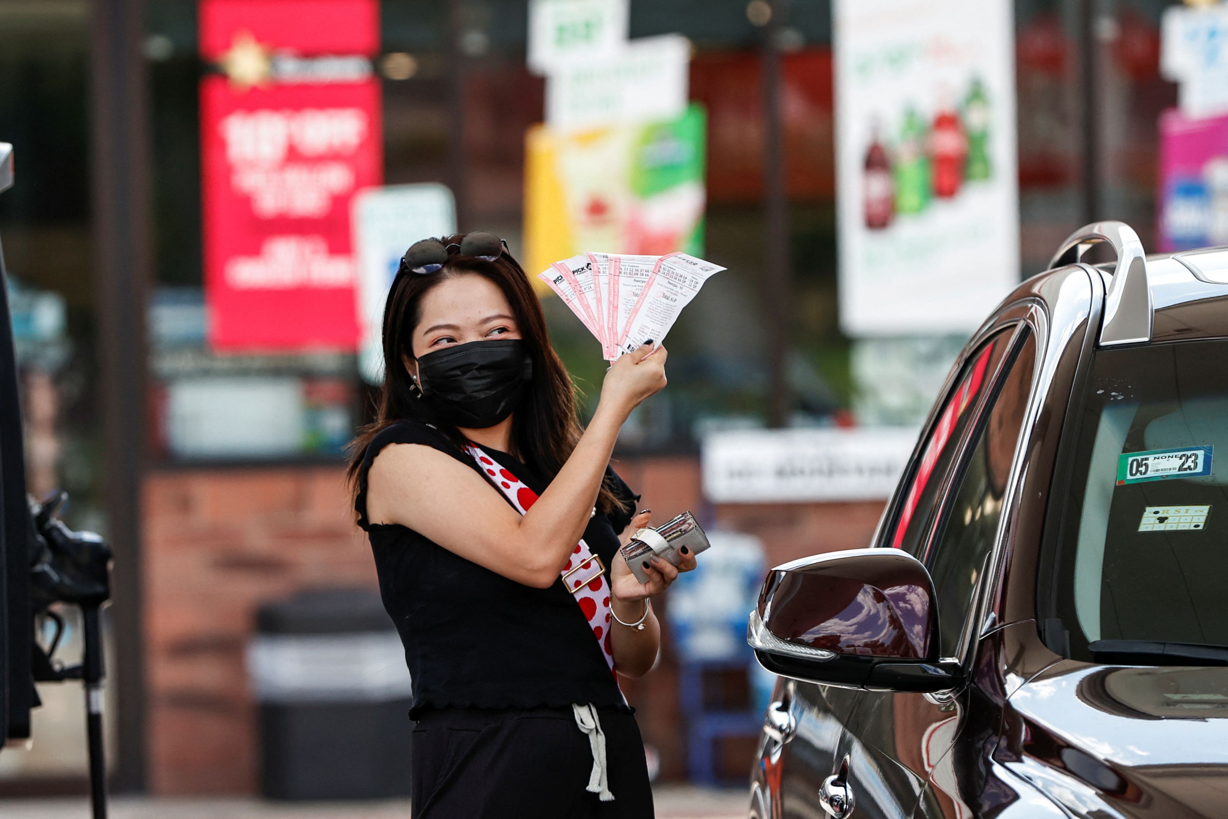 Customer Angelina Weng shows her purchased lottery tickets outside the Speedway gas station, where the winning ticket for the Mega Millions lottery jackpot was sold, in Des Plaines, Illinois, U.S. July 30, 2022. REUTERS/Kamil Krzaczynski