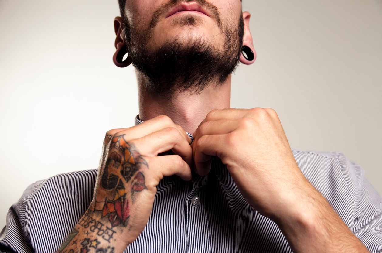 Unrecognizable hipster man with tattoos buttoning shirt , macho man, fashion shot