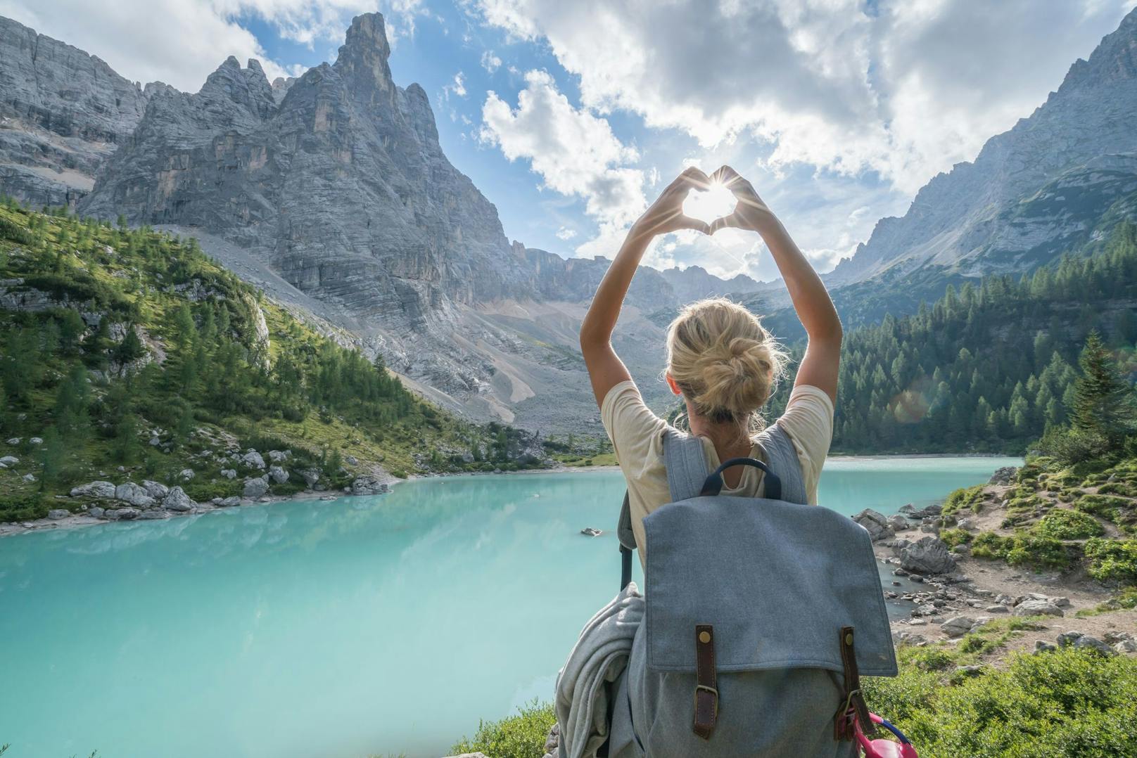 Eine junge Frau genießt die Sonnenstrahlen bei einem Alpensee in Südtirol. Symbolbild