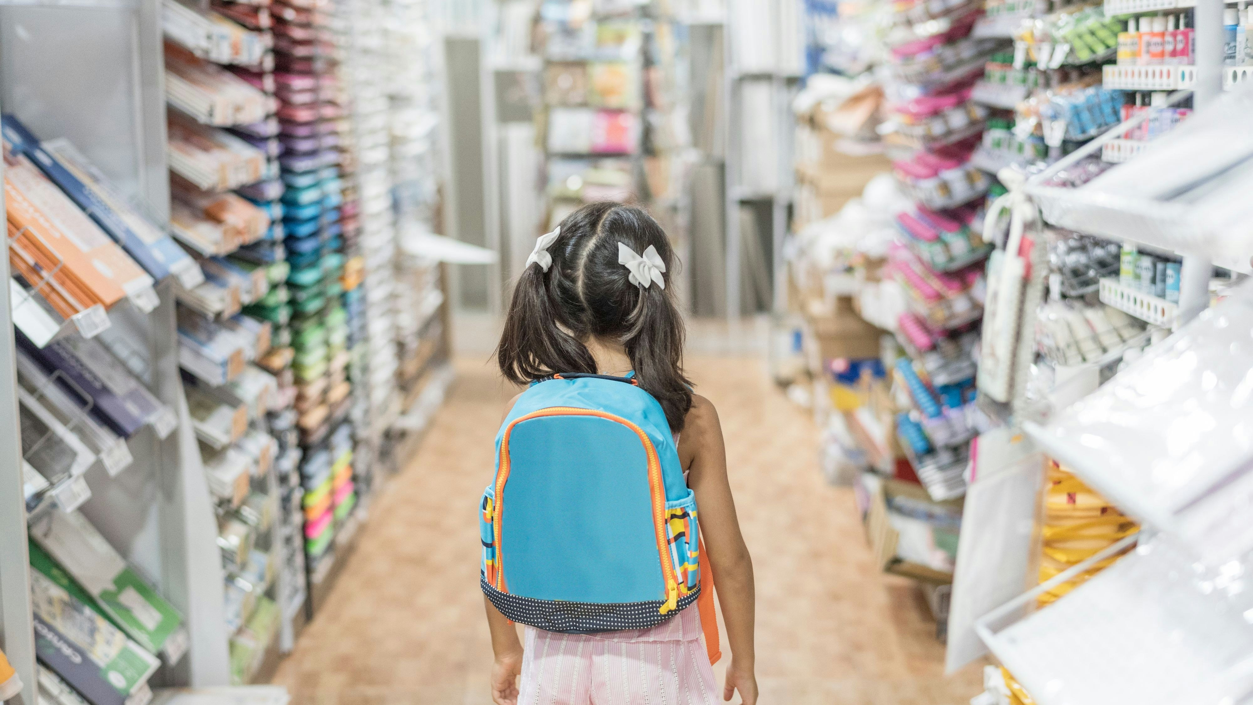 little girl in store with backpack ready for by school material
