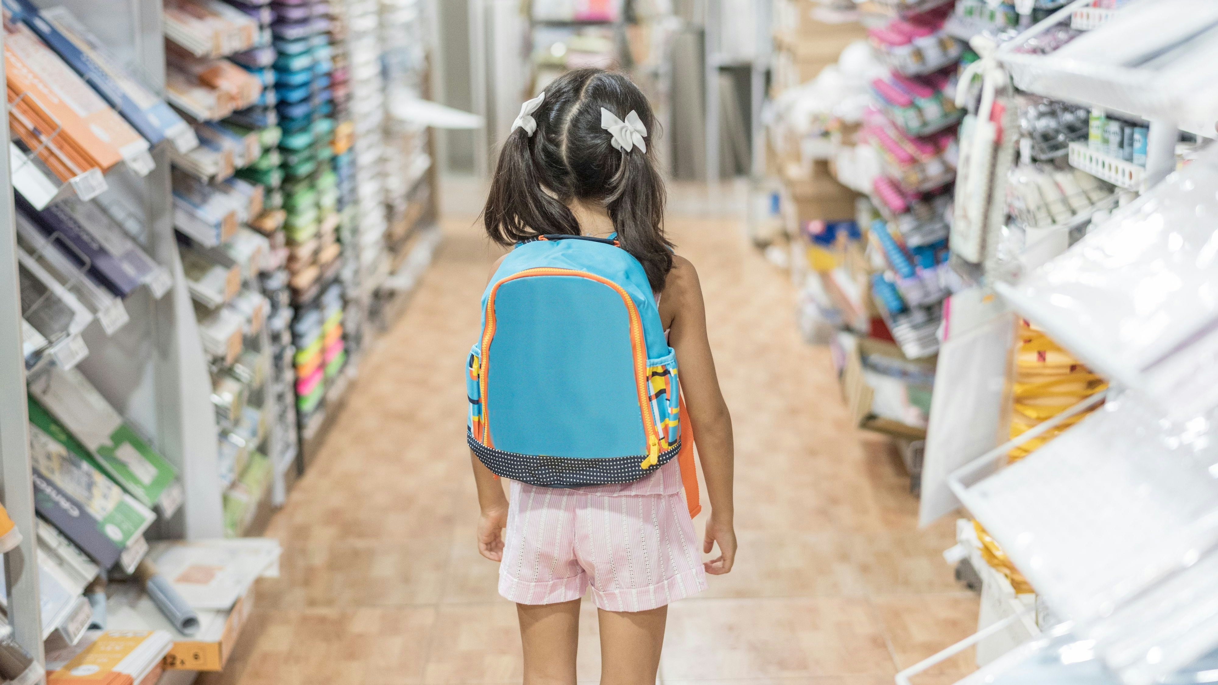 little girl in store with backpack ready for by school material