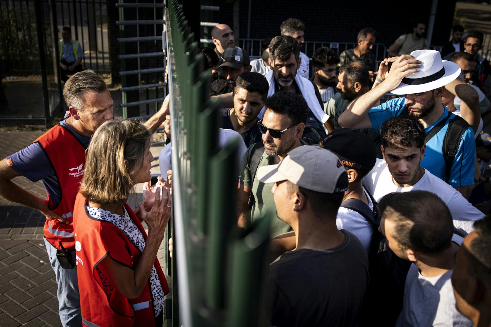 13.08.22: Asylsuchenden im Einsatzzentrum wird durch den Zaun mitgeteilt, dass sie in der nächsten Nacht draußen schlafen müssen, weil kein Transfer in reguläre oder Notunterkünfte möglich ist.