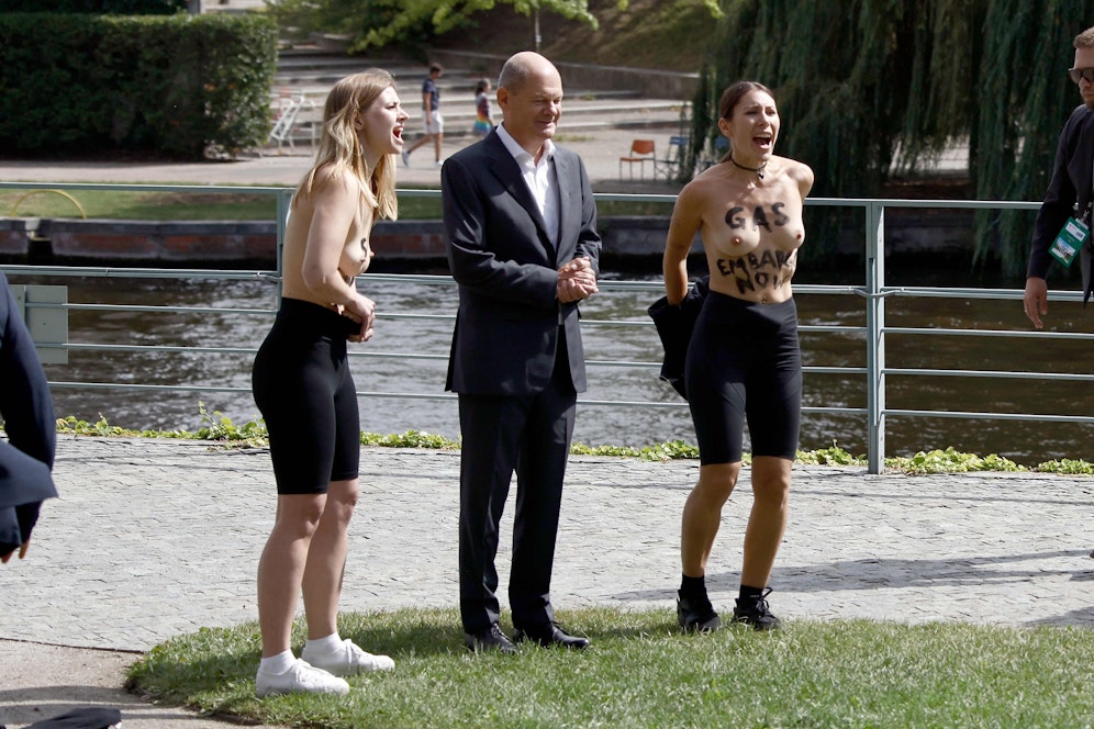 Der deutsche Kanzler ließ sich mit Bürgern fotografieren, als zwei Frauen plötzlich ihre Oberbekleidung auszogen