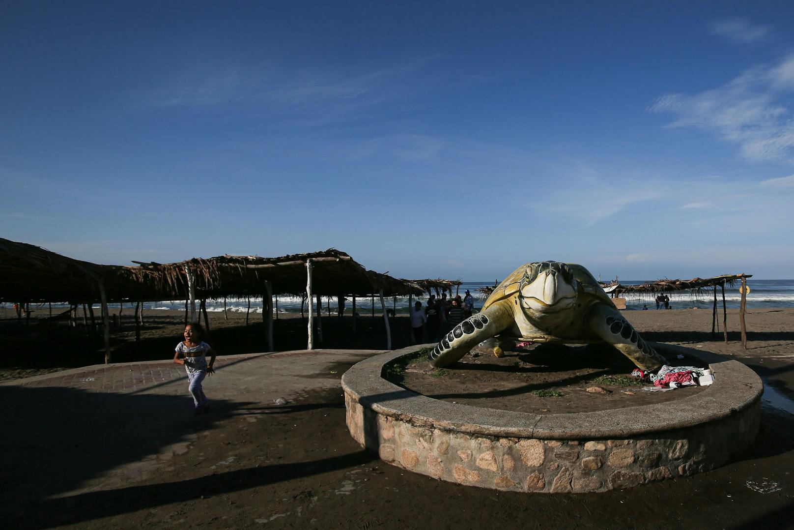Ein Kind läuft neben der Figur einer Meeresschildkröte am Eingang des Strandschutzgebietes in Puerto Arista, Mexiko.