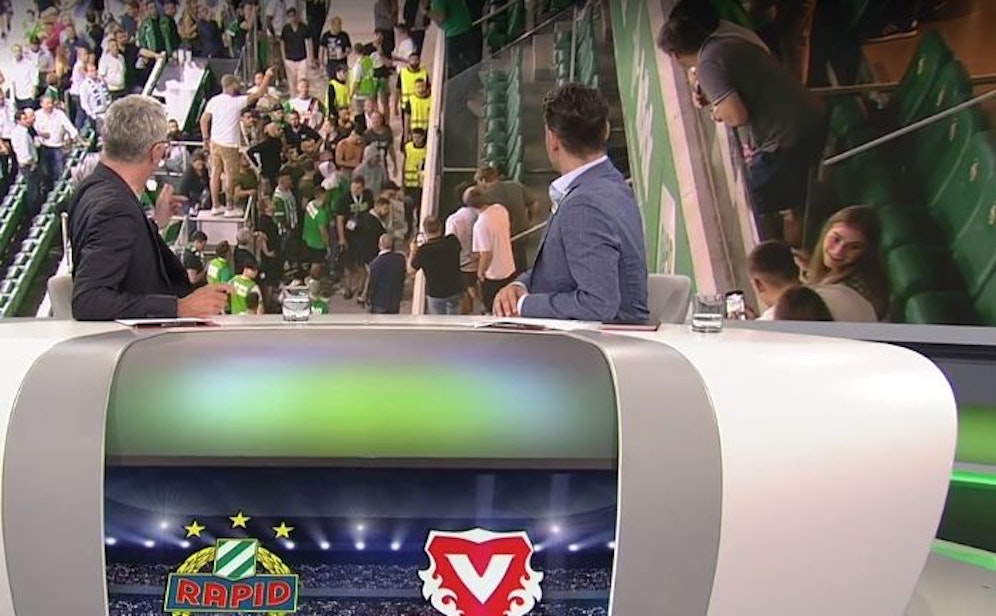 ORF-Anchor Rainer Pariasek und Experte Helge Payer sehen die Rapid-Fans beim Versuch, in den VIP-Klub vorzudringen.