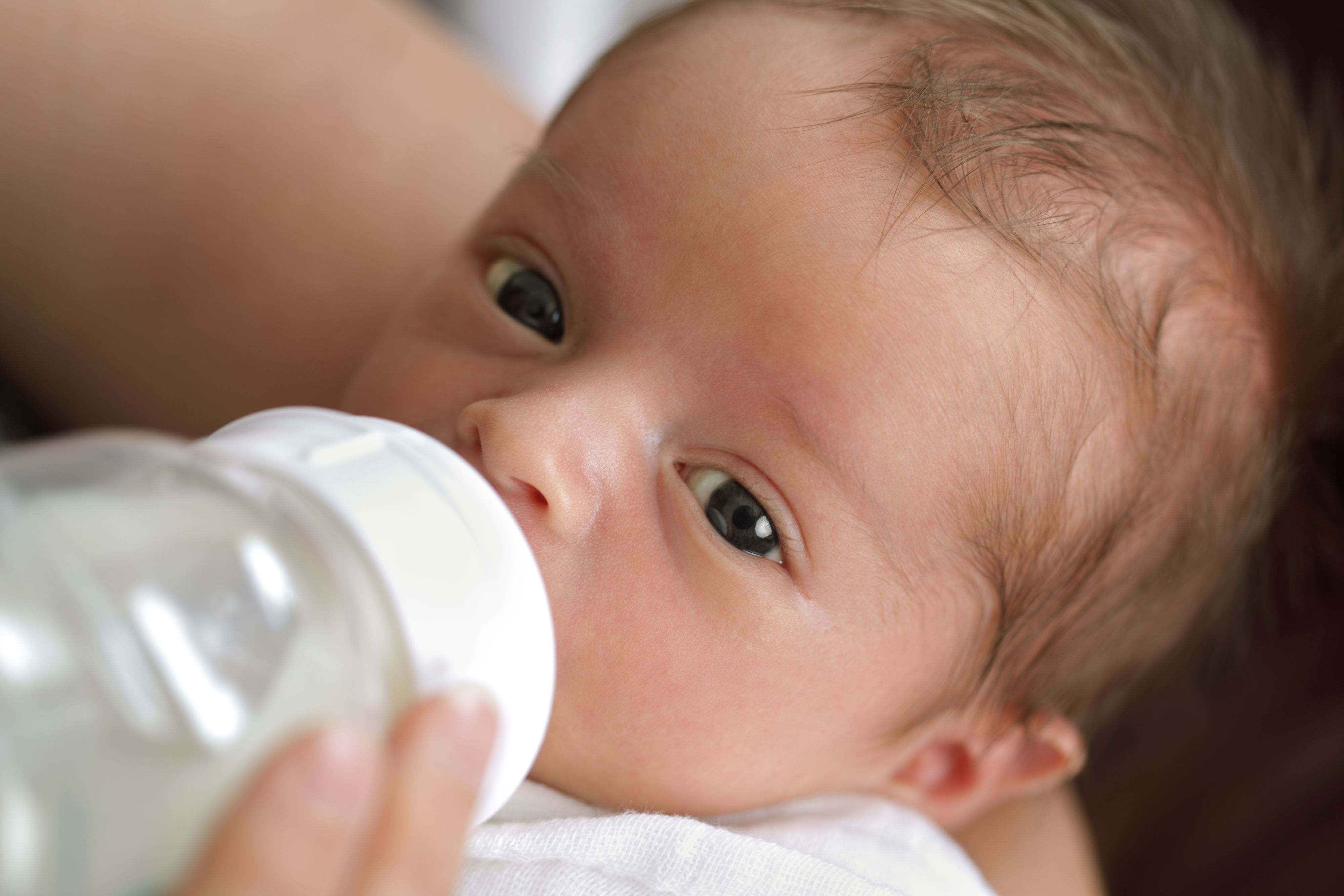 Mother holding her newborn baby boy and bottle feeding him