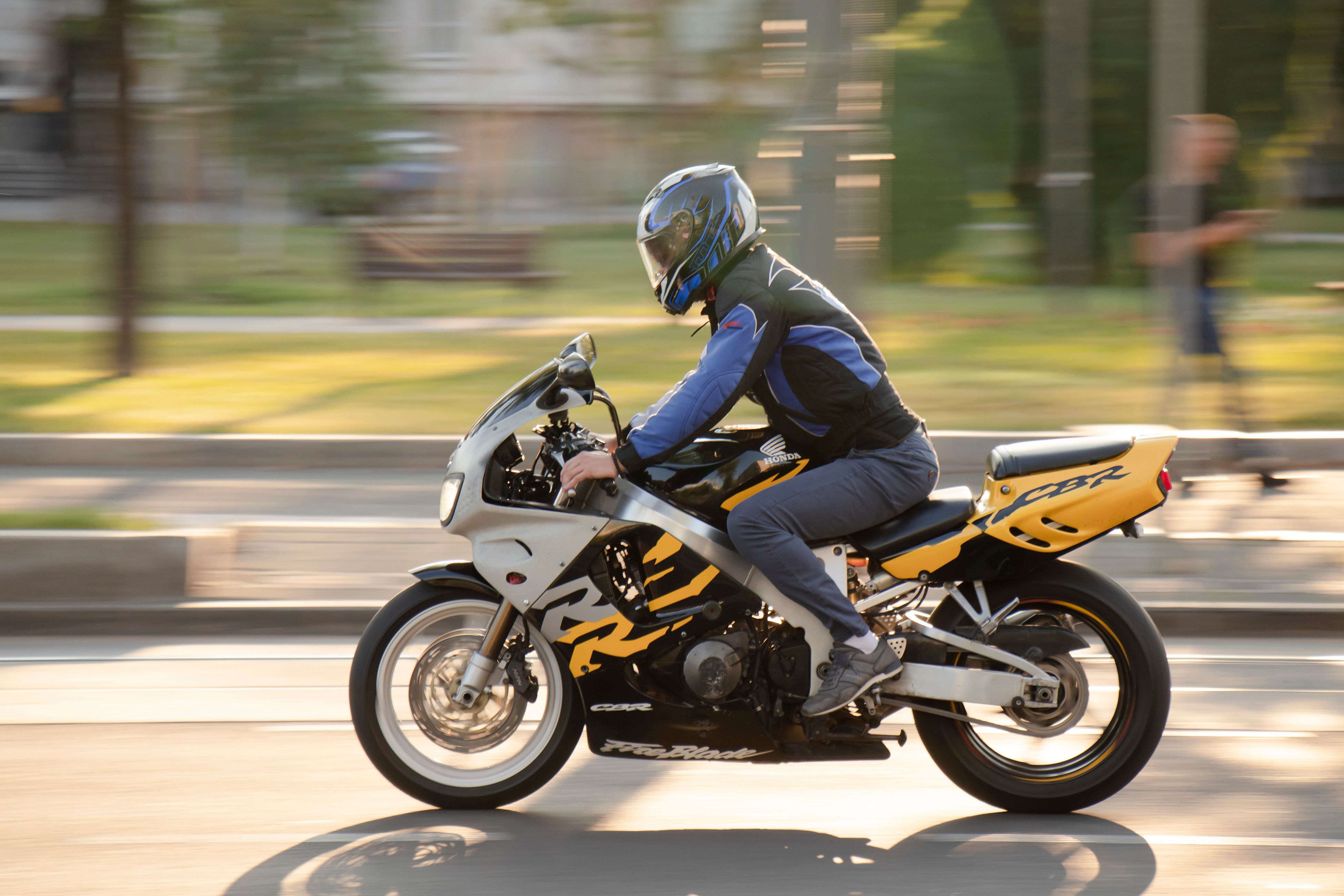 Belgrade, Serbia - July 21, 2020: Man riding a fast motorbike in empty city street by the park, in summer sunset