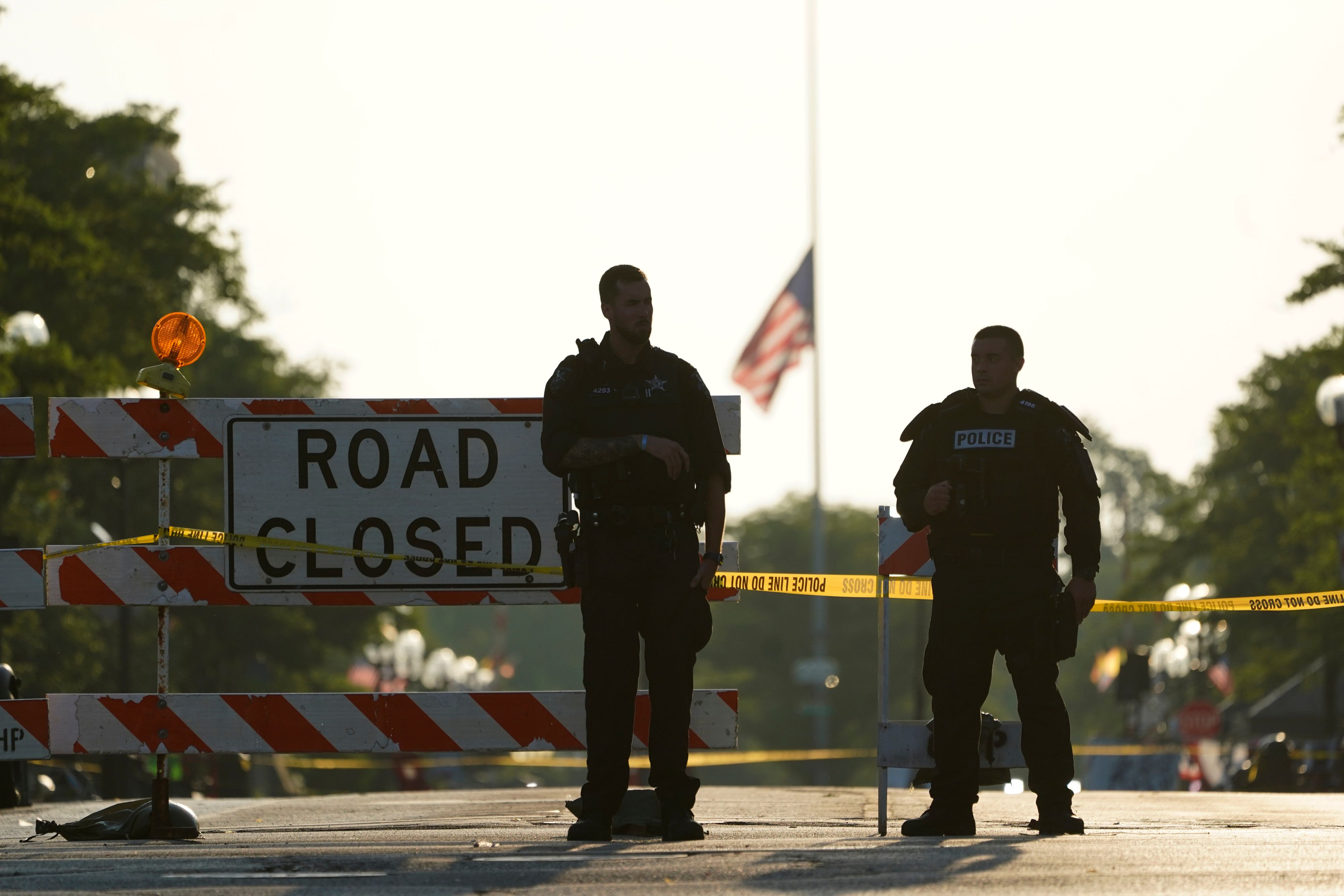 Download von www.picturedesk.com am 29.08.2022 (08:53).  Two police officers stand their post, the day after a deadly mass shooting, on the Westside of the Highland Park, Ill., Tuesday, July 5, 2022, as the American flag flies at half-staff on the Eastside. A shooter fired on an Independence Day parade from a rooftop spraying the crowd with gunshots initially mistaken for fireworks before hundreds of panicked revelers of all ages fled in terror. (AP Photo/Charles Rex Arbogast) - 20220705_PD3586 - Rechteinfo: Rights Managed (RM)