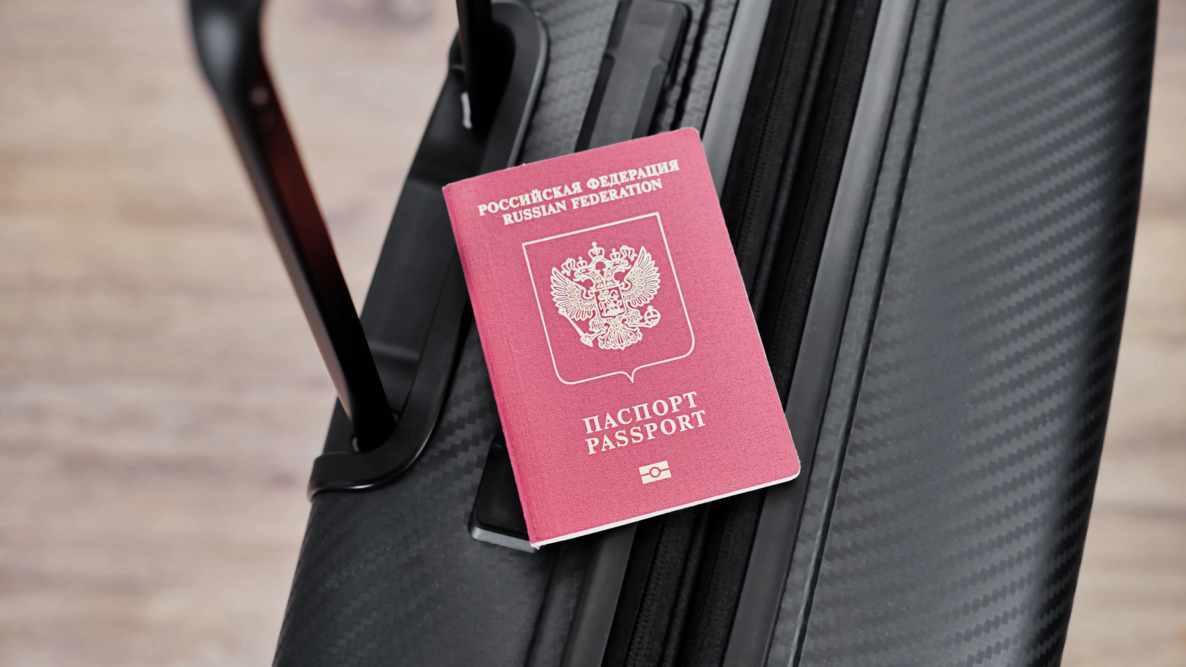 Russian passport on a black travel suitcase, top view, selective background. Emigration of Russians, seeking asylum