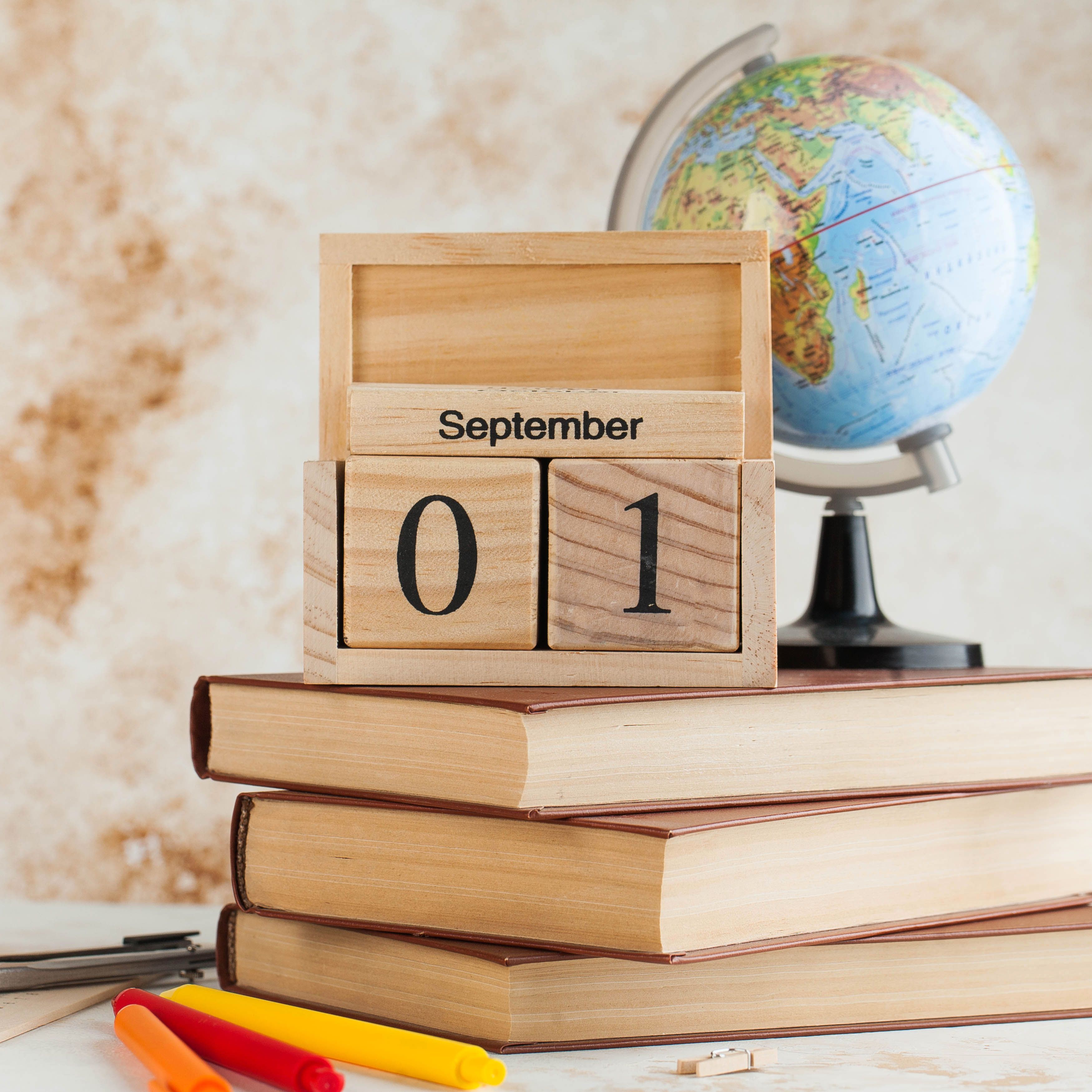 Wooden calendar September 1 on a stack of books, globe. Concept for Knowledge Day, beginning of school year. Copy space. High quality photo