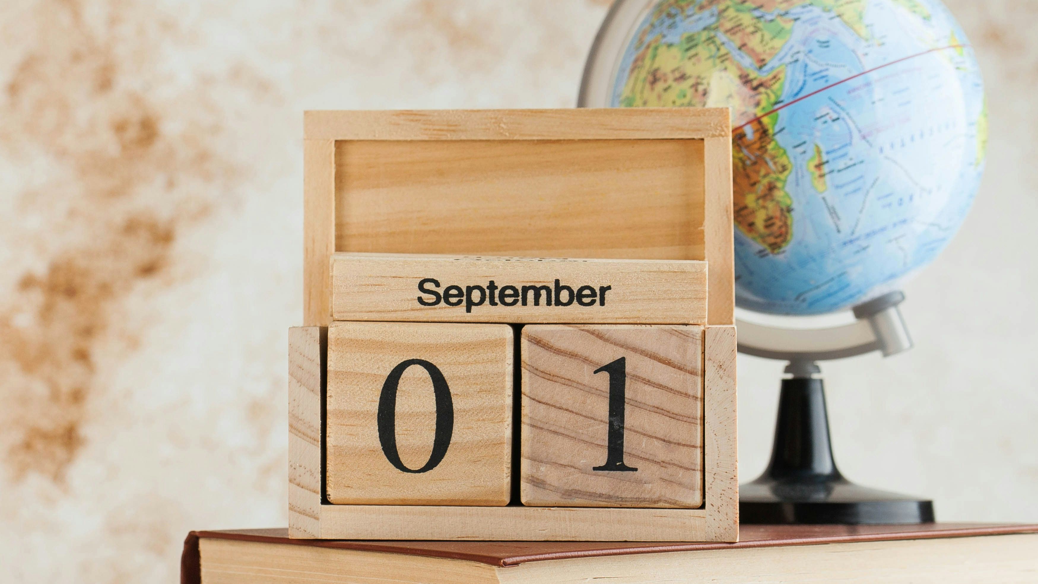 Wooden calendar September 1 on a stack of books, globe. Concept for Knowledge Day, beginning of school year. Copy space. High quality photo