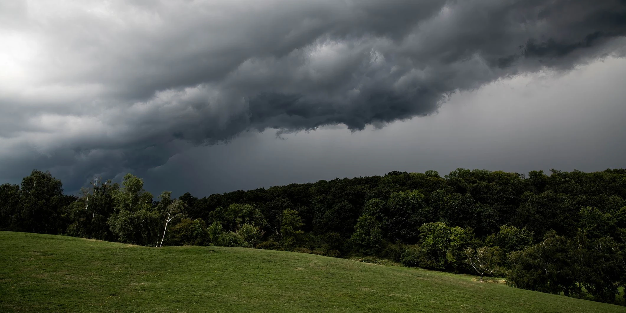 Gewitterwolken über einem Hügel. Symbolbild