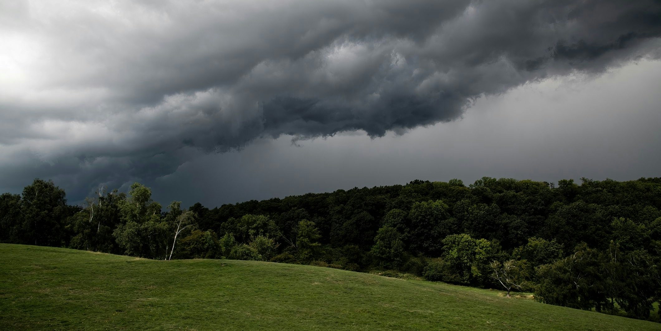 Gewitterwolken über einem Hügel. Symbolbild