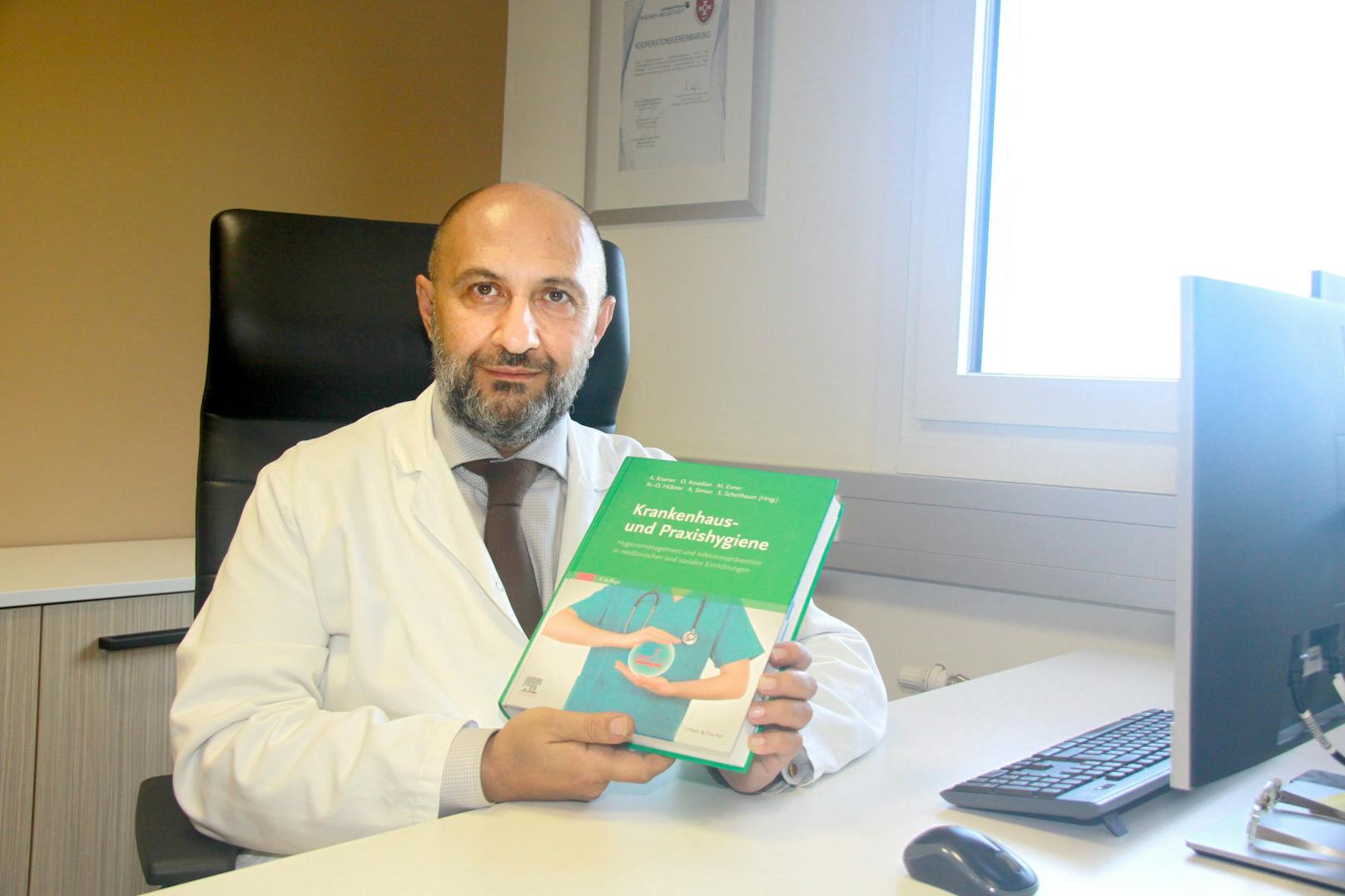 Univ.-Prof. Dr. Ojan Assadian mit seinem Buch.