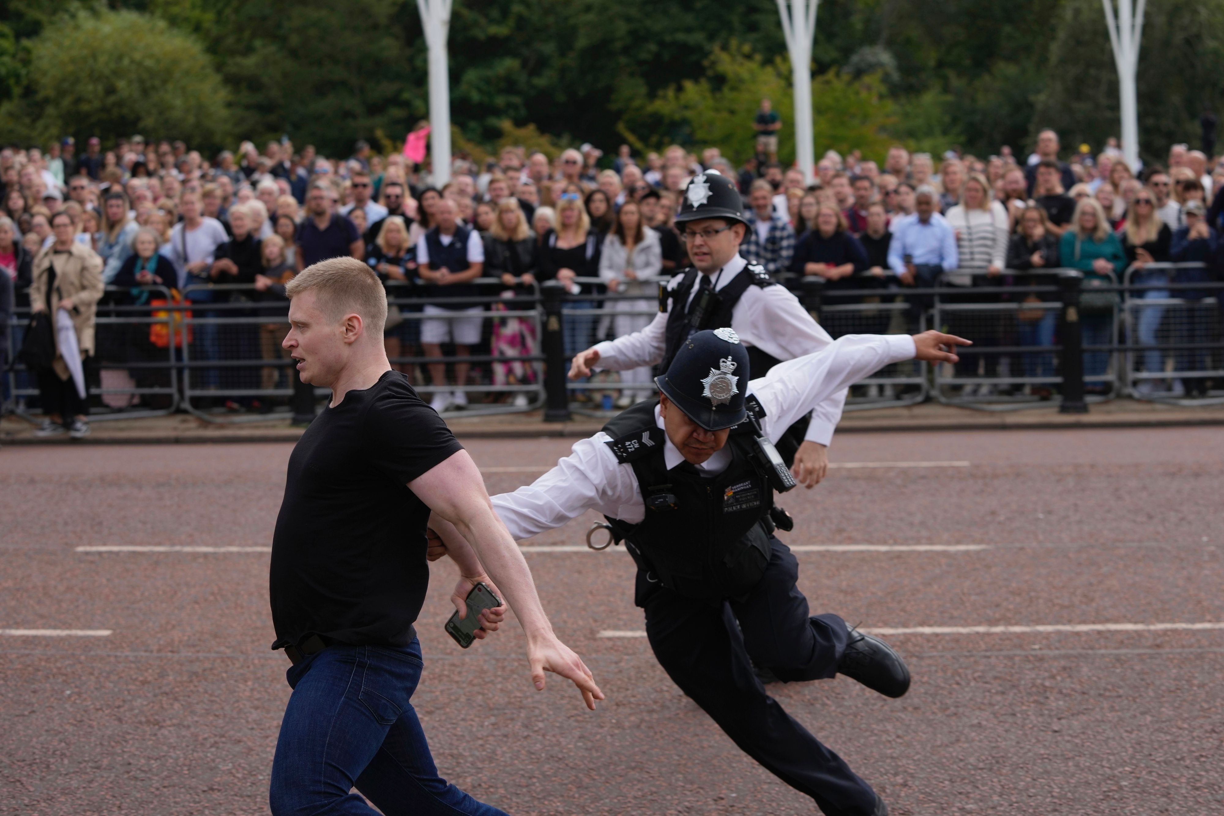 Kurz bevor King Charles III. über die Prachtstraße fuhr, sprang ein Mann über die Absperrung. Die Polizei nahm den Mann am Samstag vor dem Buckingham-Palast fest.