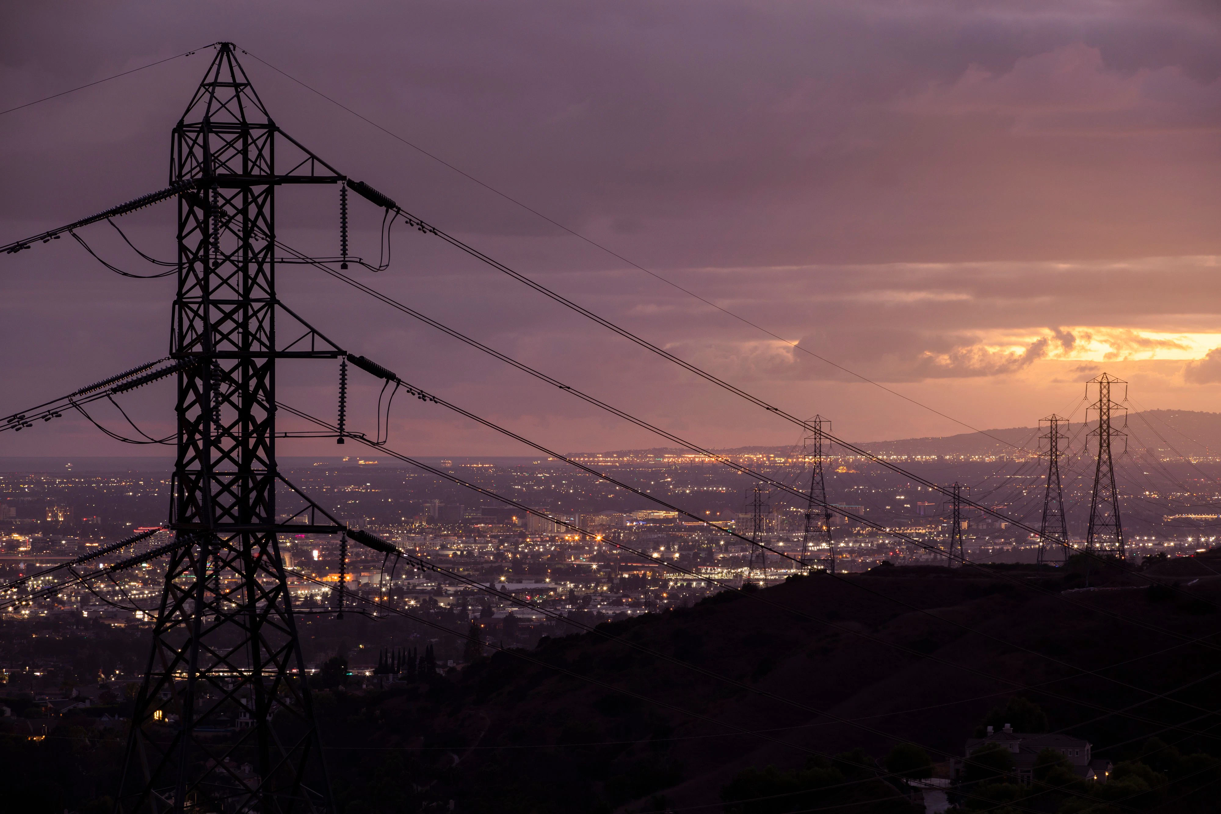 Sunset view of power transmission lines in the hills above Villa Park, with the southern Californian basin below, USA.