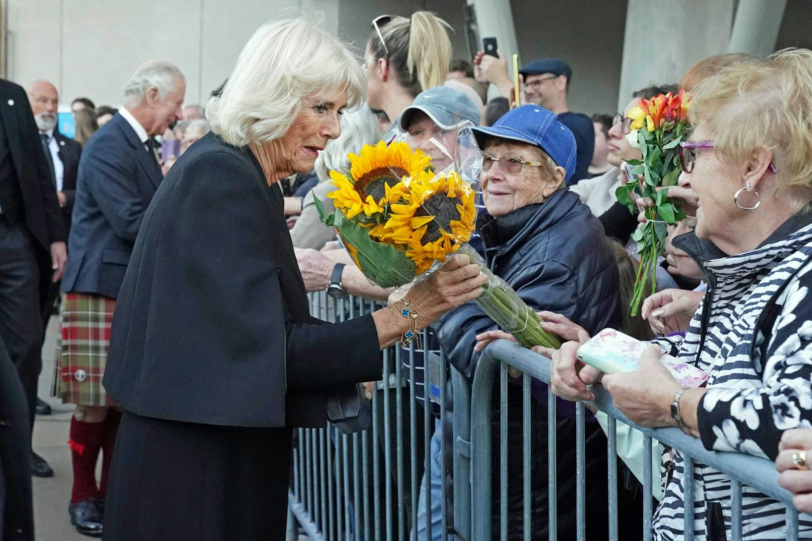 Die trauernde Bevölkerung überreicht der neuen Queen Consort Blumen.