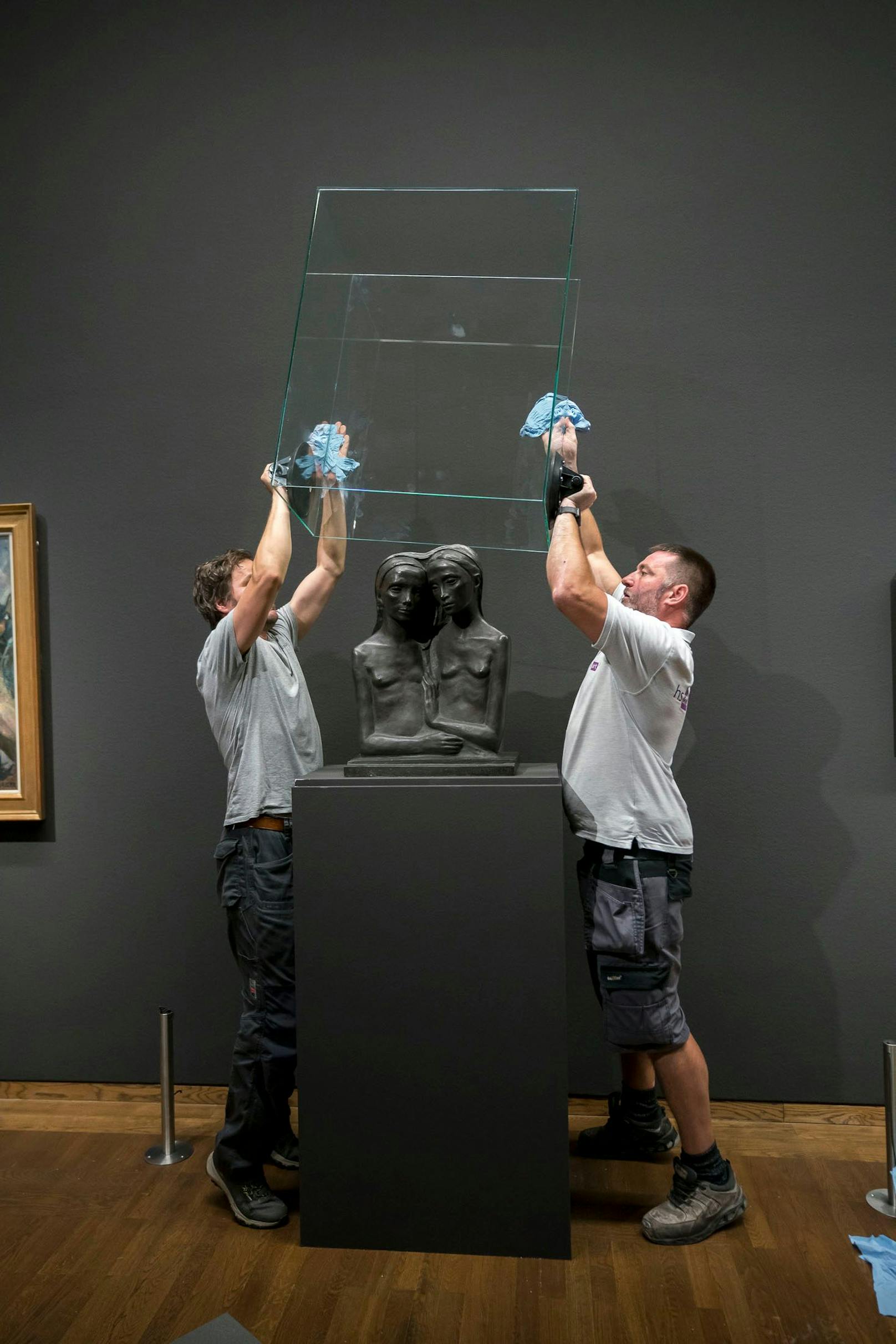 Arbeiter stülpen einen schützenden Glaskobel über die Skulptur "Zwei Schwestern" von Georg Ehrlich.