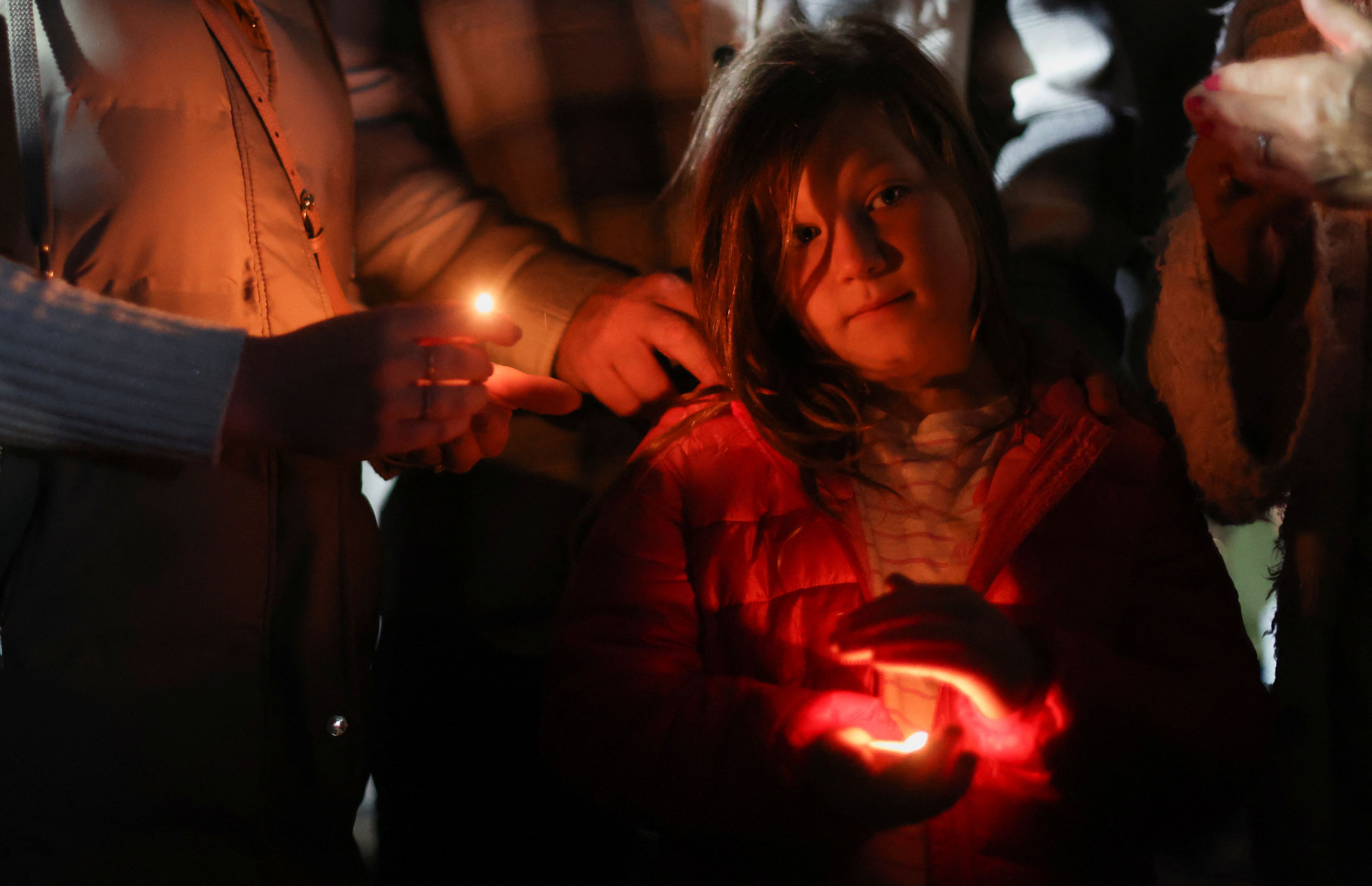 A girl holds a candle as people attend a "National moment of reflection" in honour of the late Queen Elizabeth II, the day before her funeral, in Windsor, Britain September 18, 2022. REUTERS/Carl Recine