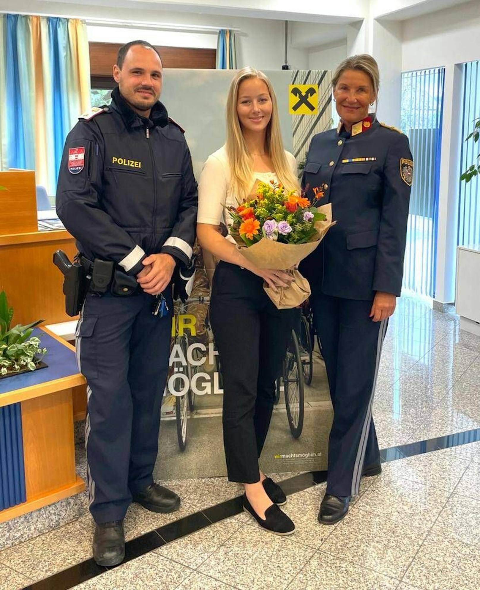 Polizei-Bezirkskommandantin Sonja Fiegl und Patrick Weiss-Hubner danken Katharina Doppler für ihre Zivilcourage mit einem Blumenstrauß.