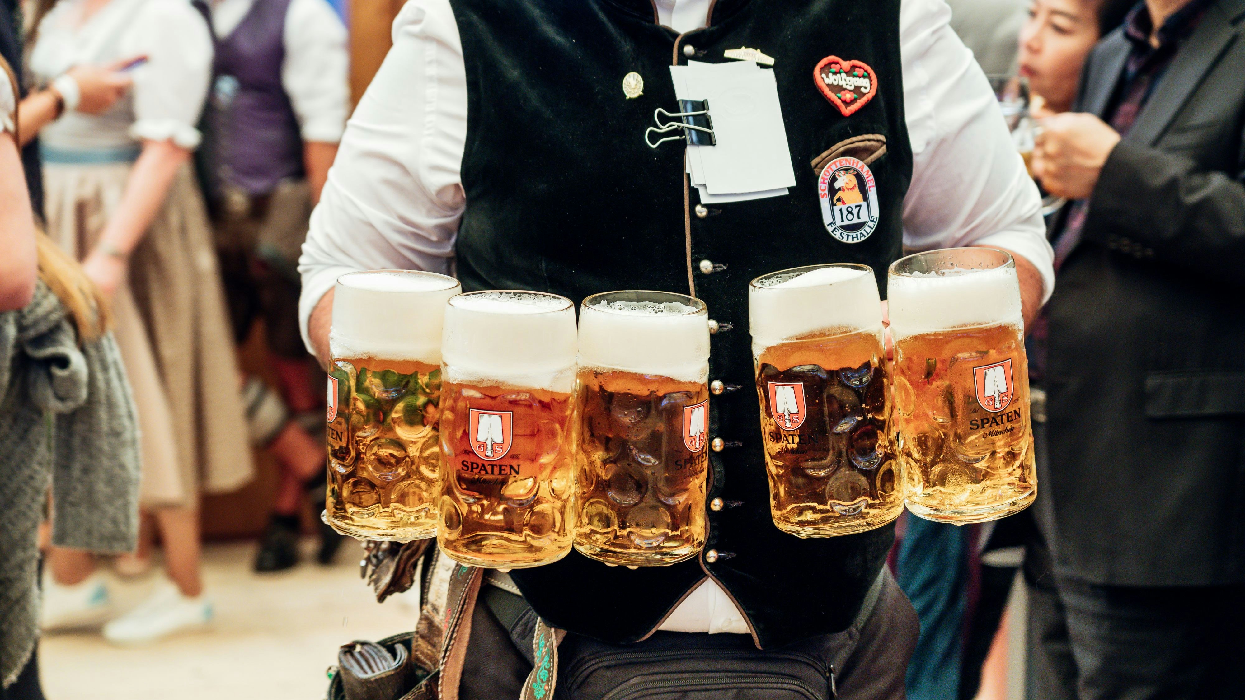 Munich, Germany - September 21, 2019: waiter carrying a lot of beer glasses in beer garden at Octoberfest in Munich.