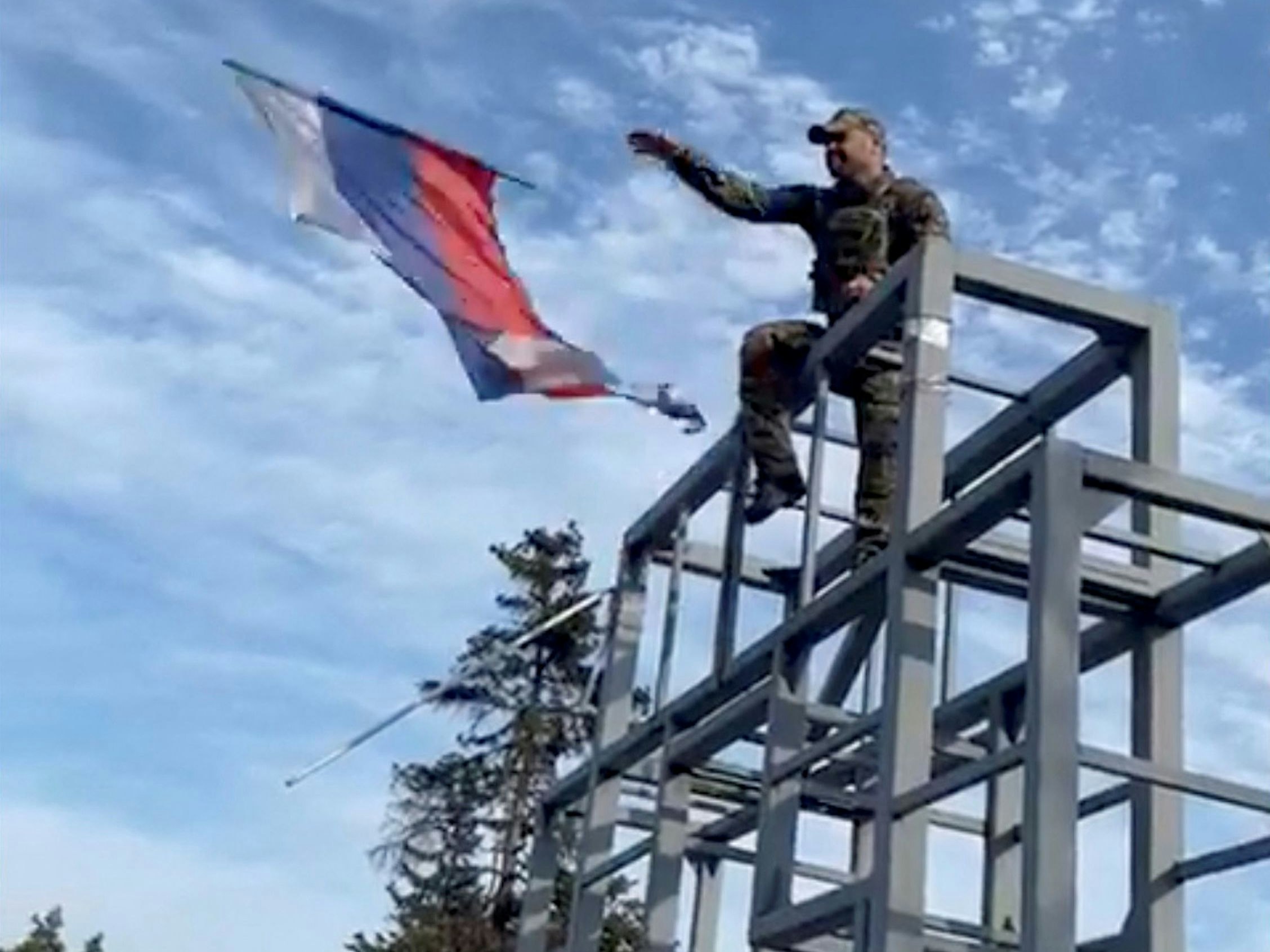 A member of the Ukrainian troop brings down a Donetsk Republic flag hoisted on a monument in Lyman, Ukraine in this screen grab obtained from social media video released on October 1, 2022. Oleksiy Biloshytskyi/via REUTERS  THIS IMAGE HAS BEEN SUPPLIED BY A THIRD PARTY. MANDATORY CREDIT. NO RESALES. NO ARCHIVES.