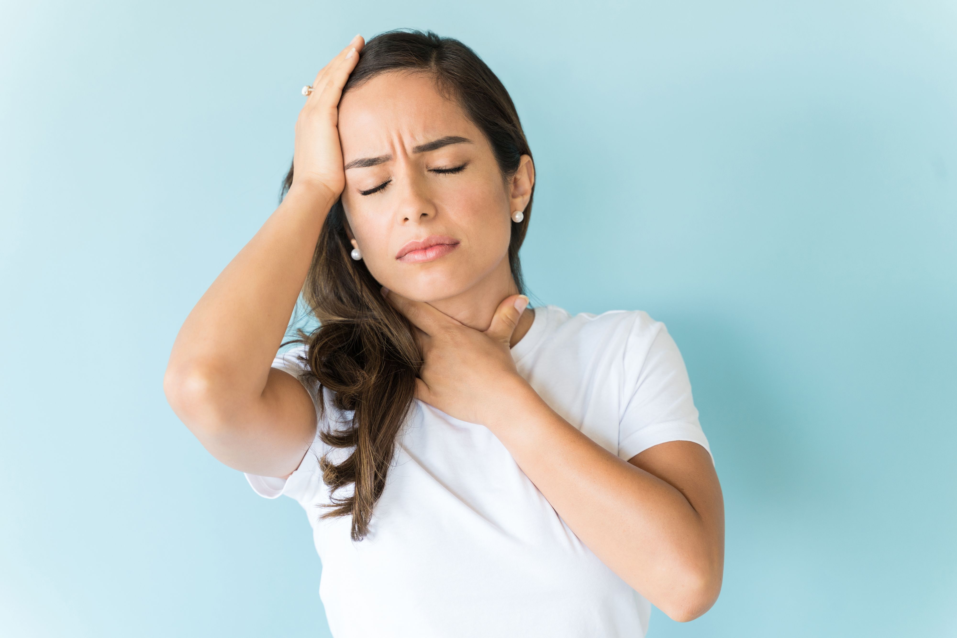 Unhappy ill woman suffering from headache and throat pain against colored background