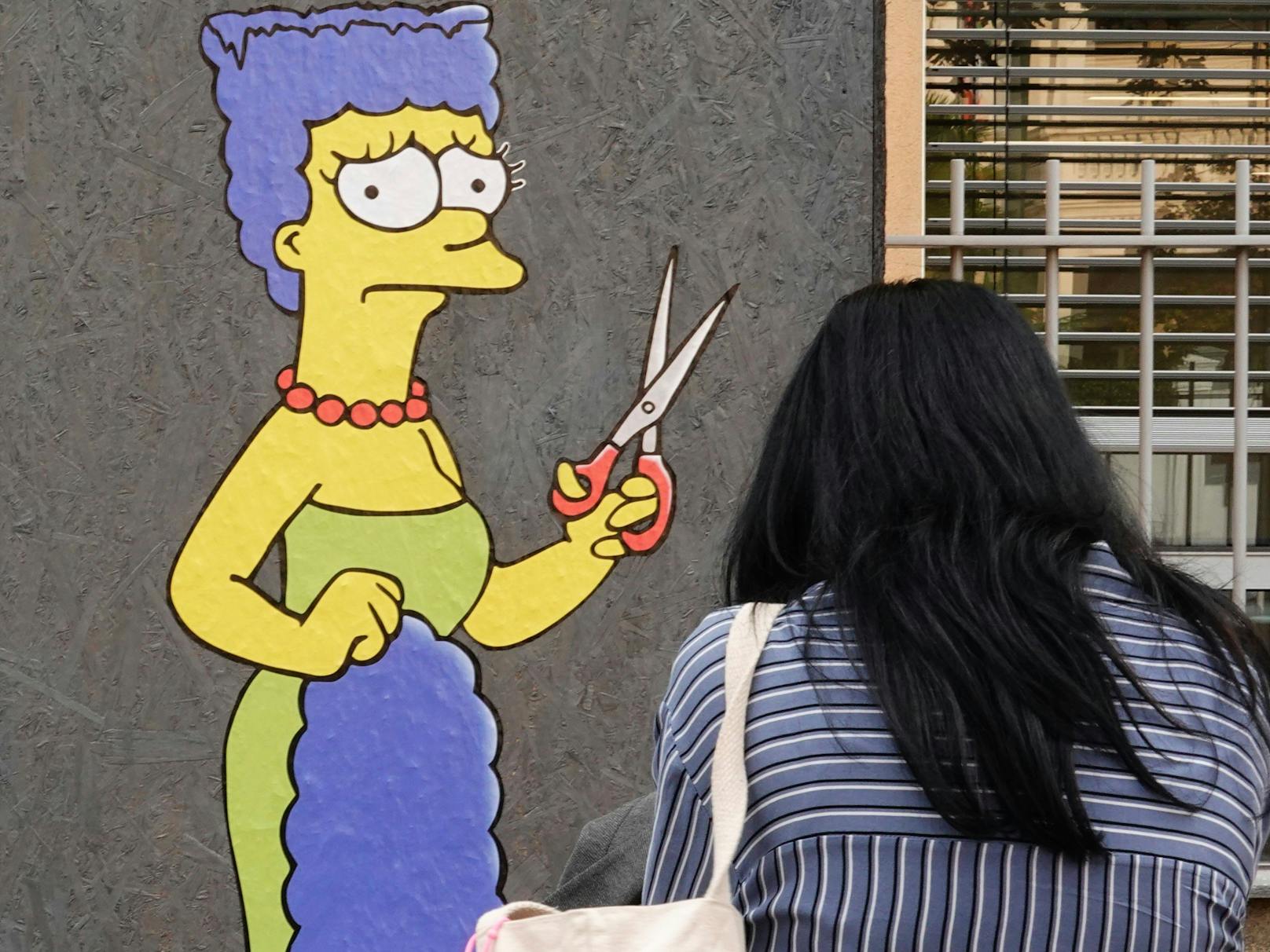 Der Straßenkünstler Alexsandro Palombo zeichnete vor dem iranischen Konsulat in Mailand die Comicfigur Marge Simpson, die sich aus Protest und Solidarität mit dem Schicksal von Mahsa Amini die Haare abgeschnitten hat.