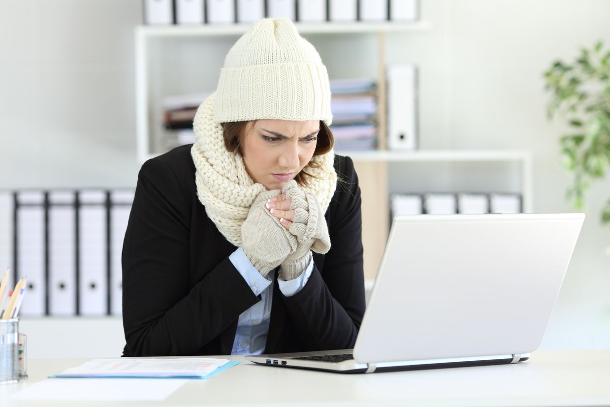 Cold angry executive working at office with a heater failure in winter