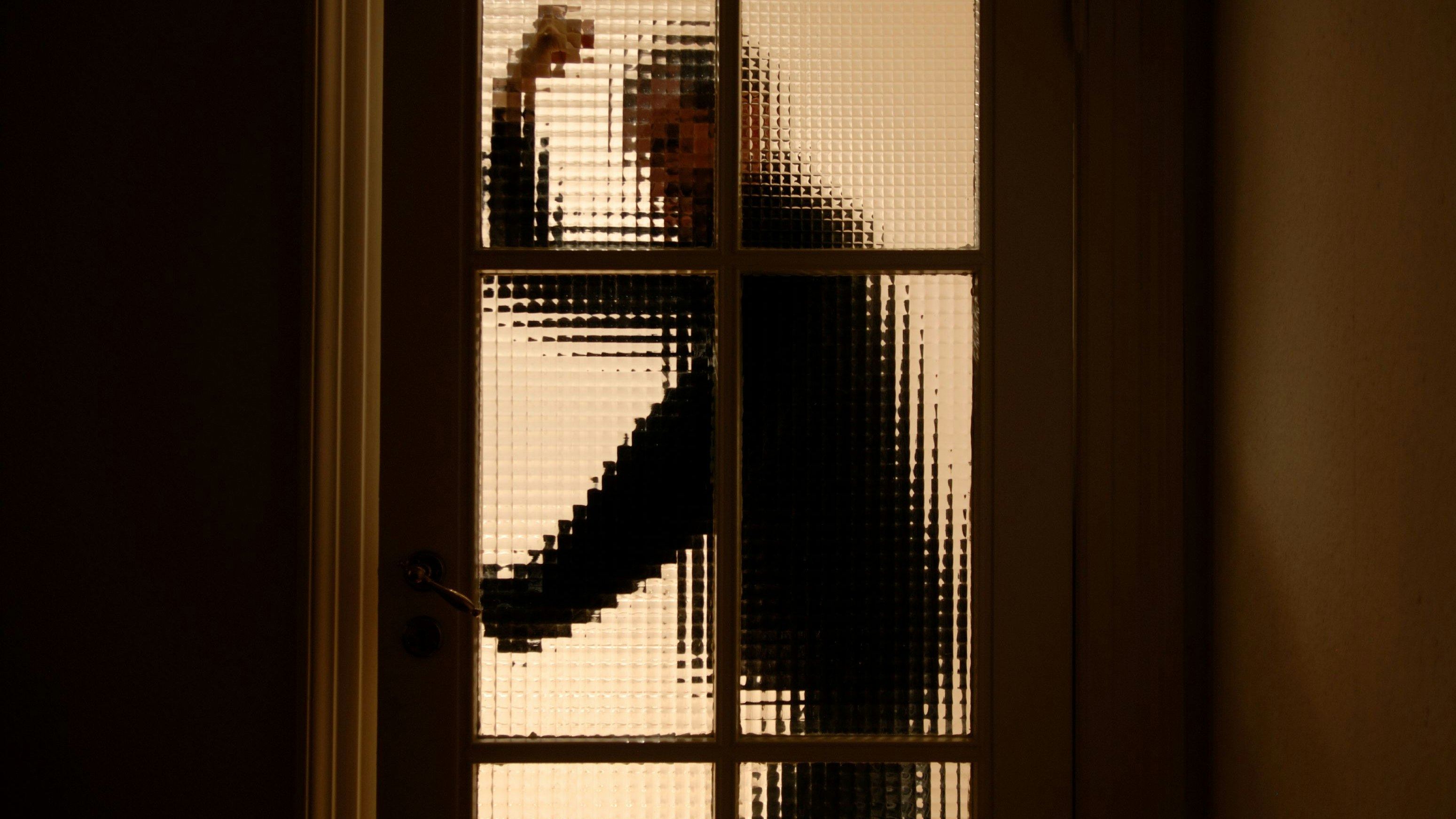 An aggressive and violent man on his way through a partially transparent glass door (entering a dark room).