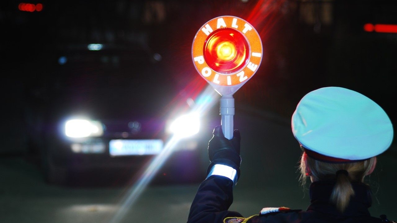 Eine Polizeibeamtin fordert einen Pkw-Lenker zum Anhalten auf. Symbolbild.