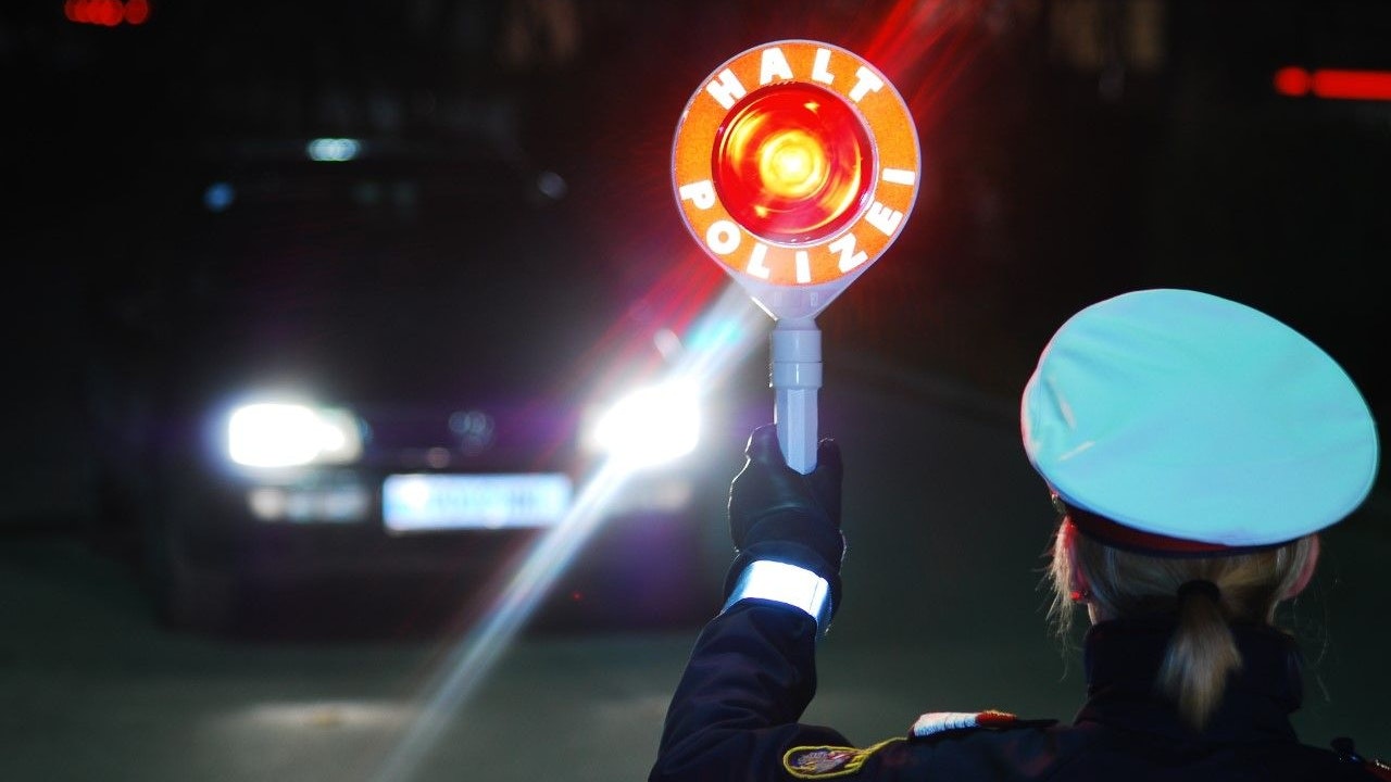 Eine Polizeibeamtin fordert einen Pkw-Lenker zum Anhalten auf. Symbolbild.